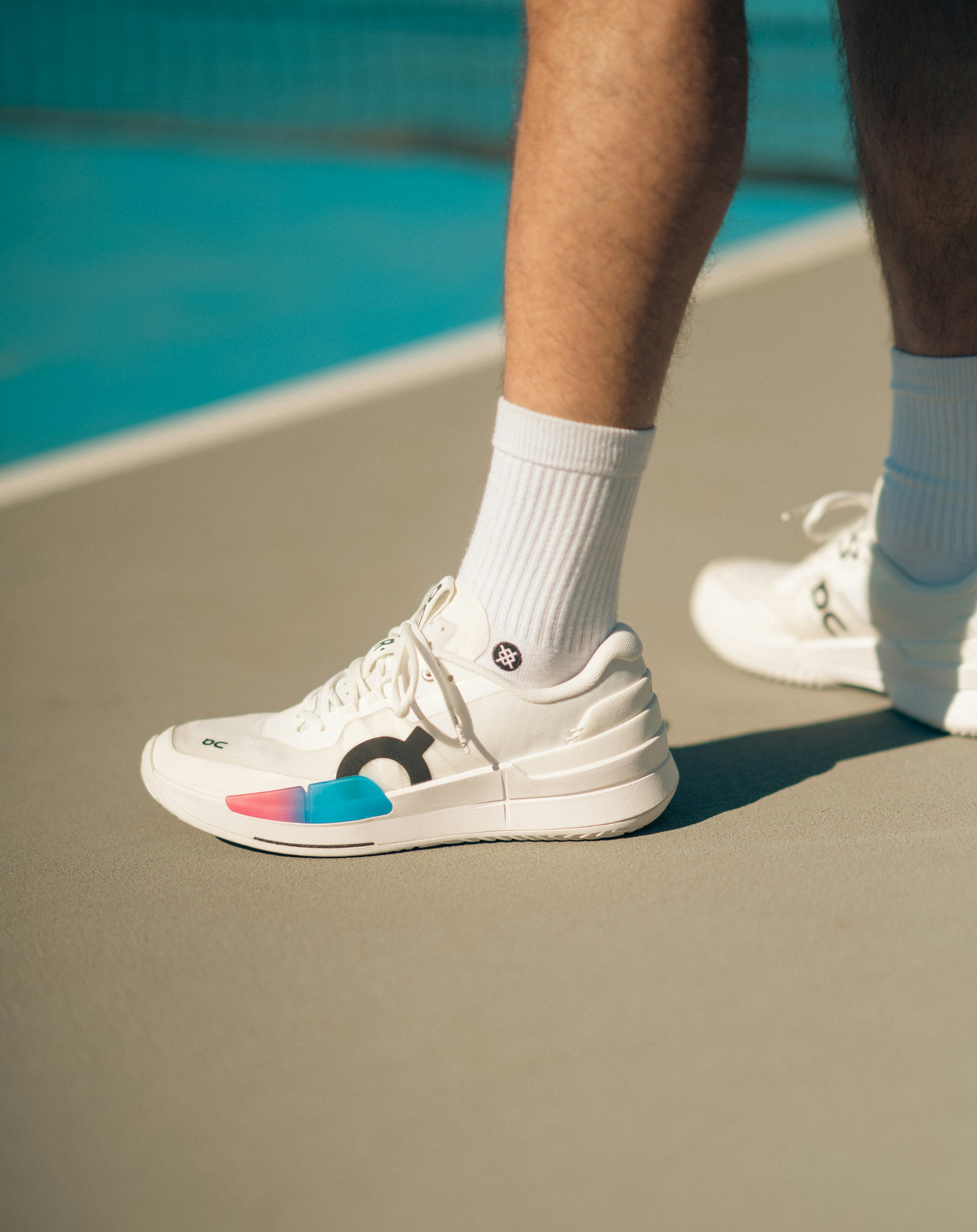 Una persona de pie en una cancha de tenis con zapatos de tenis blancos
