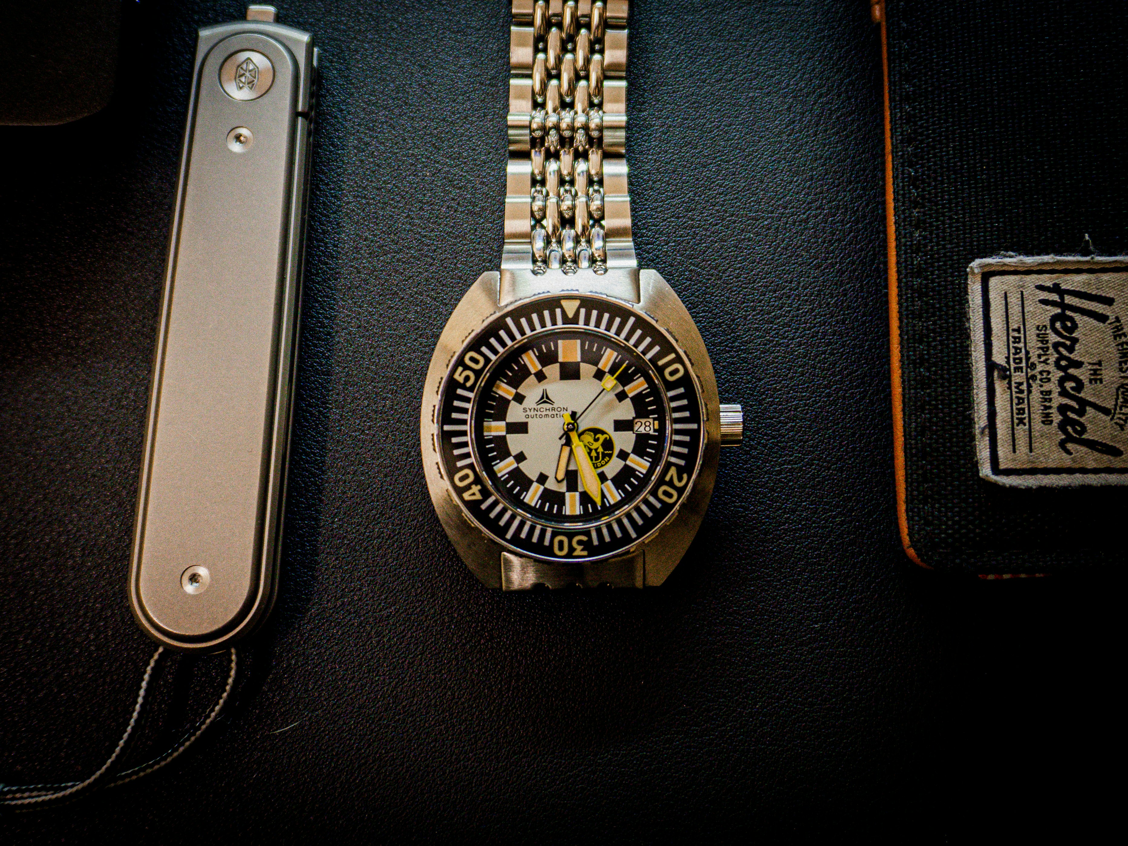 A watch sitting on top of a table next to a remote control
