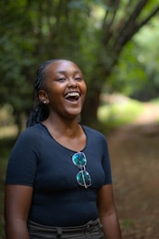 A woman laughing while standing in the woods