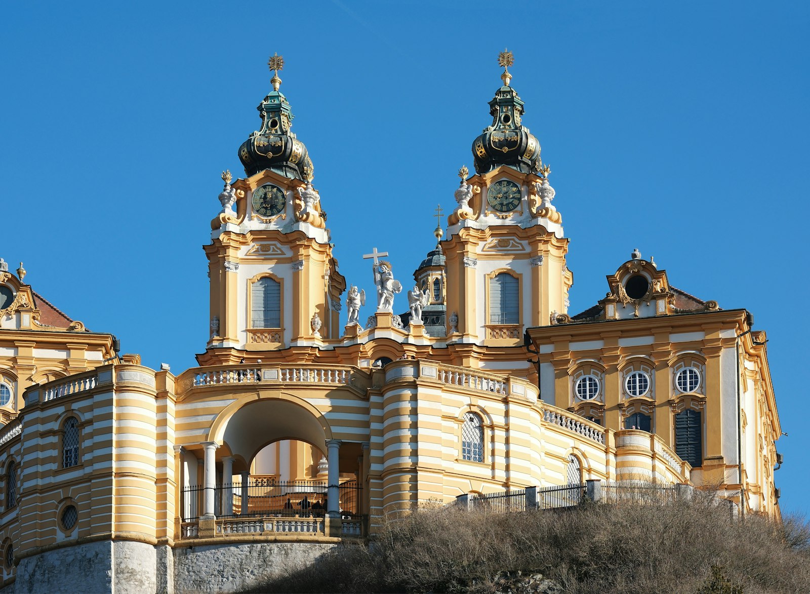 The twin Baroque towers and golden facade of Melk Abbey against a deep blue sky