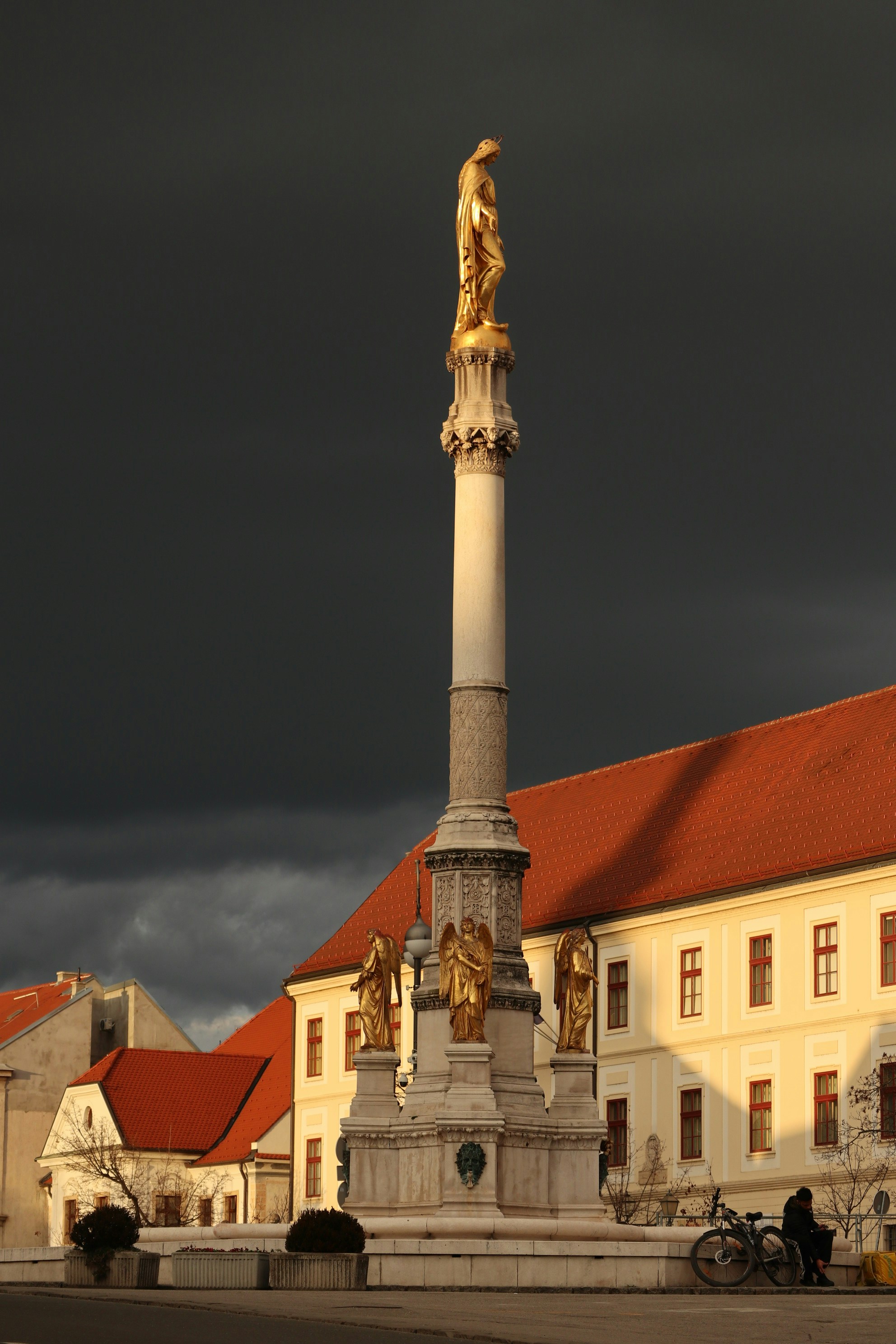 A statue in front of a building under a cloudy sky