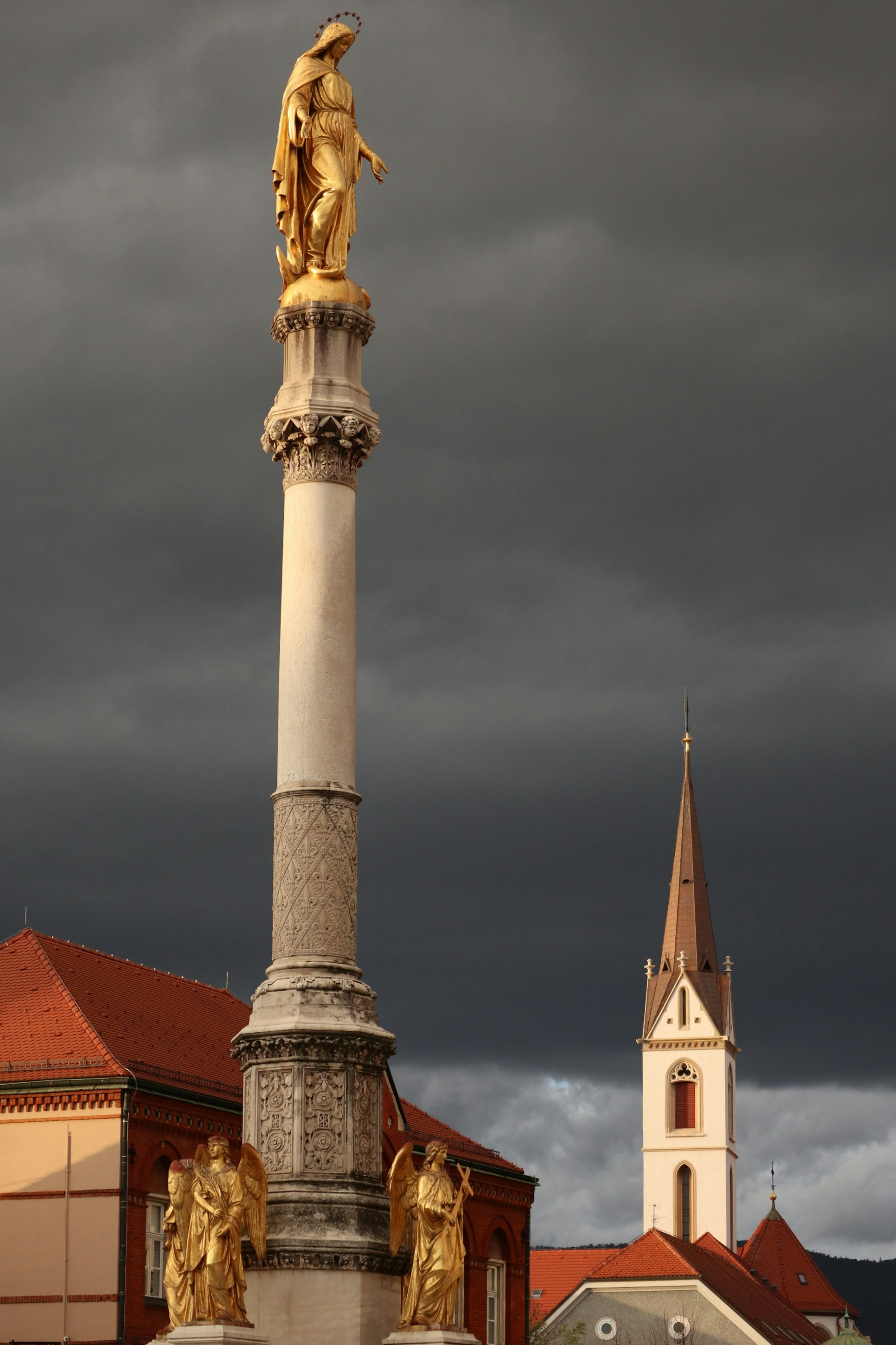 A statue on top of a pillar with a clock tower in the background
