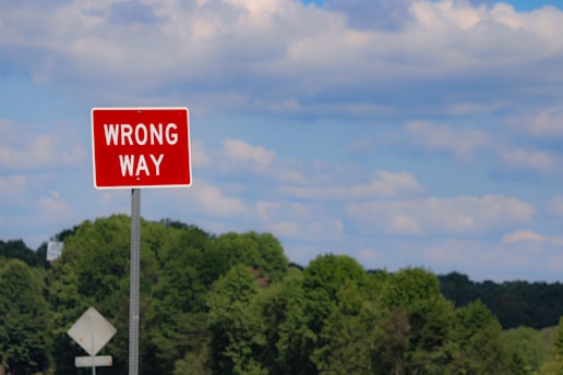 A red wrong way sign sitting on the side of a road