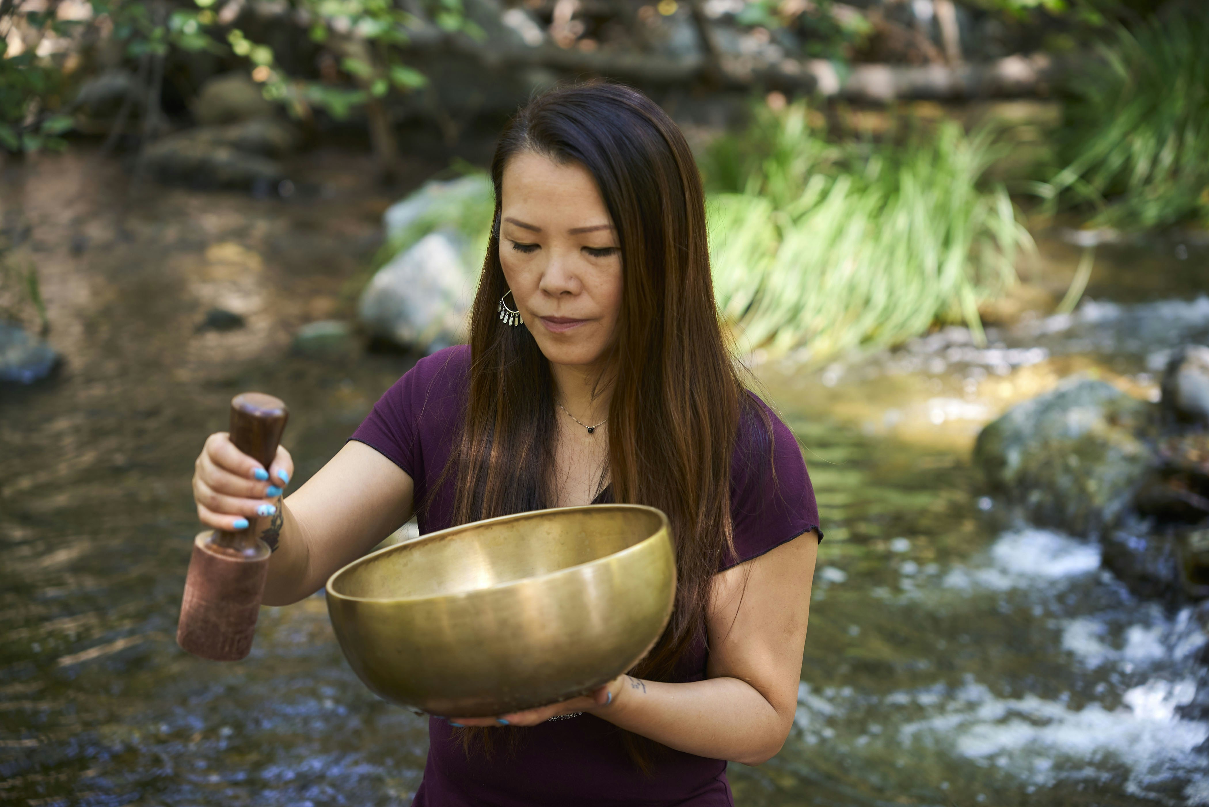 A woman standing in a stream holding a large bowl