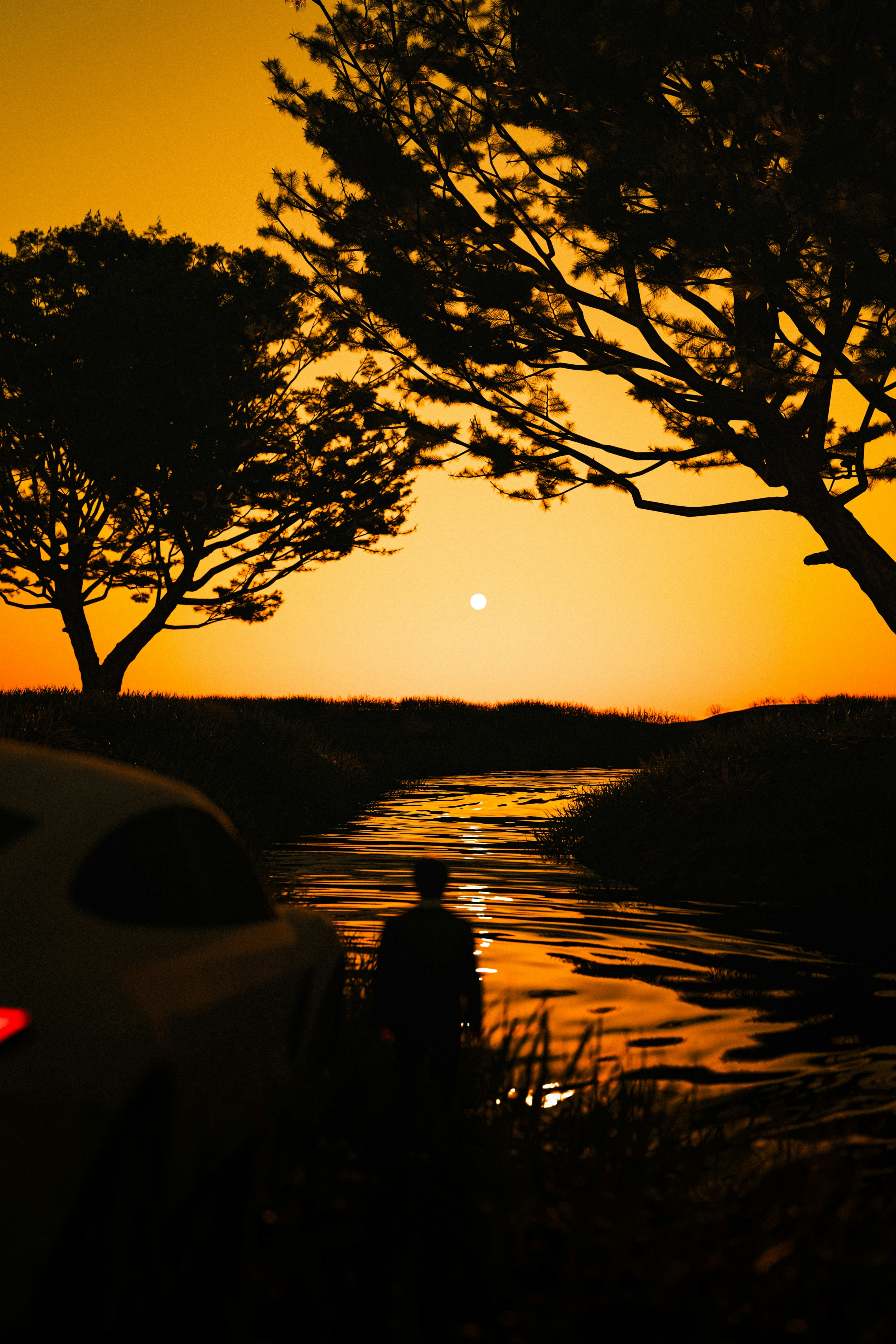 A car parked next to a body of water at sunset