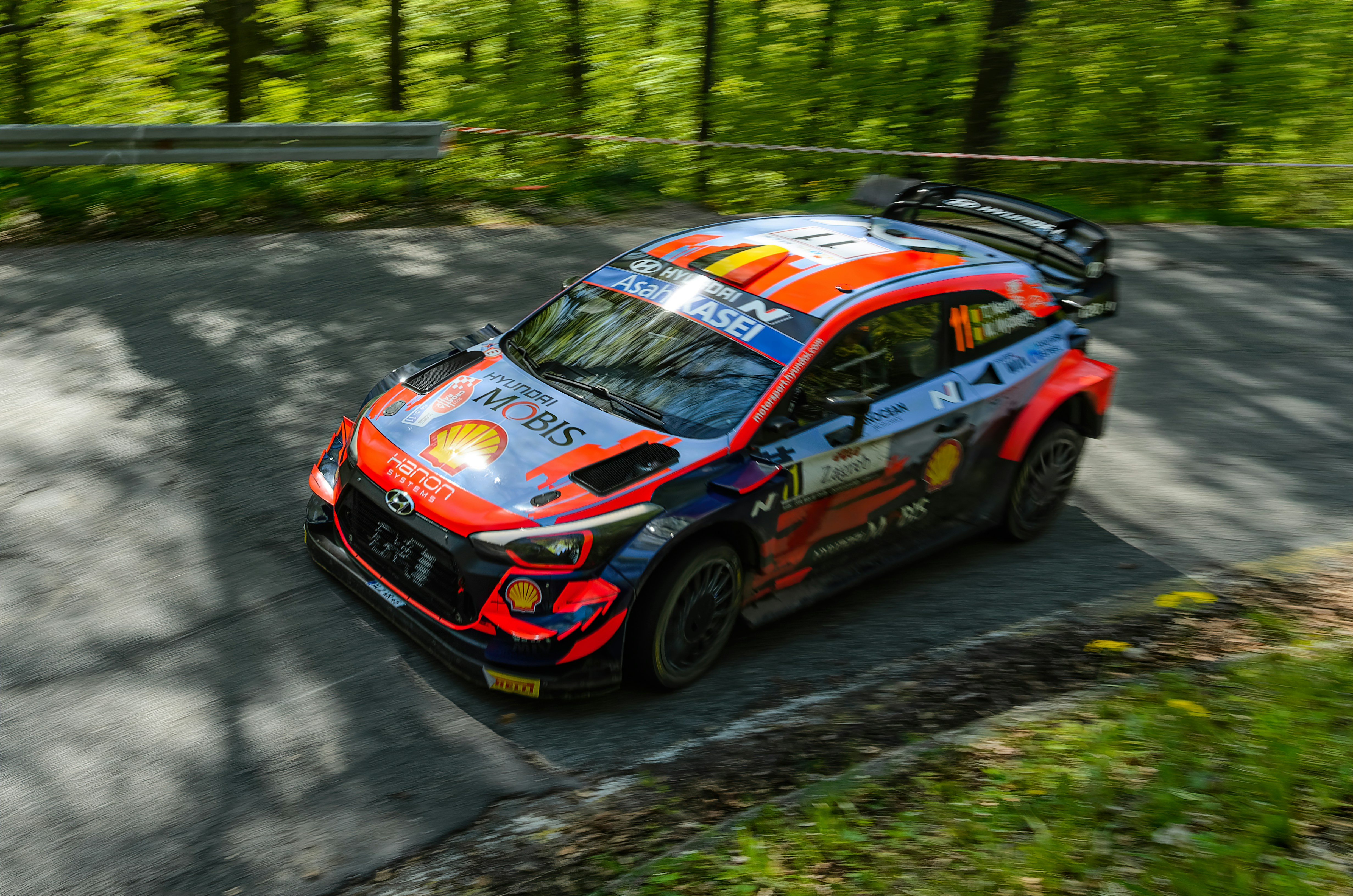 A car driving down a road with trees in the background