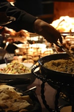 A person is serving food from a buffet table