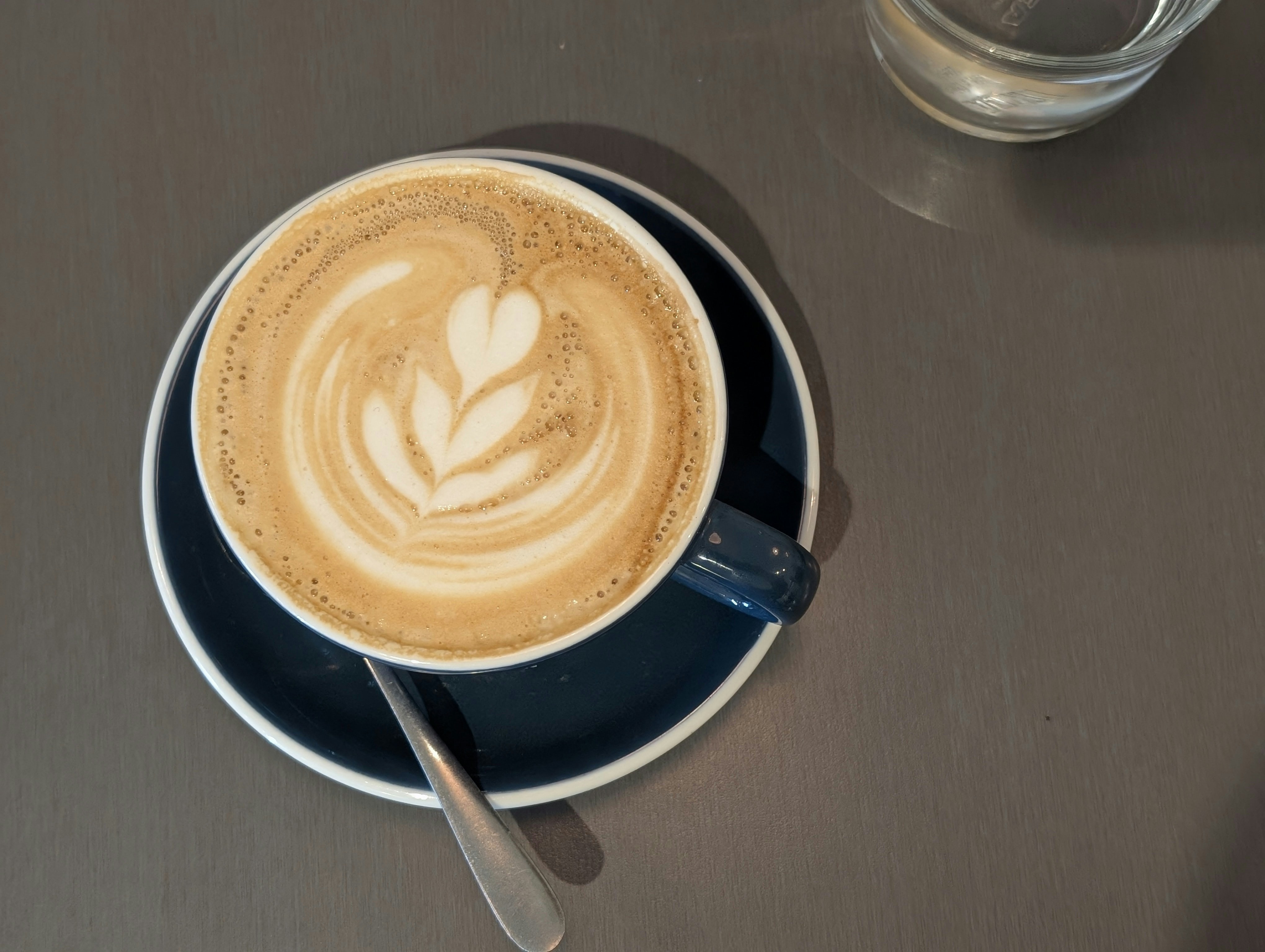 A cup of coffee on a saucer with a spoon