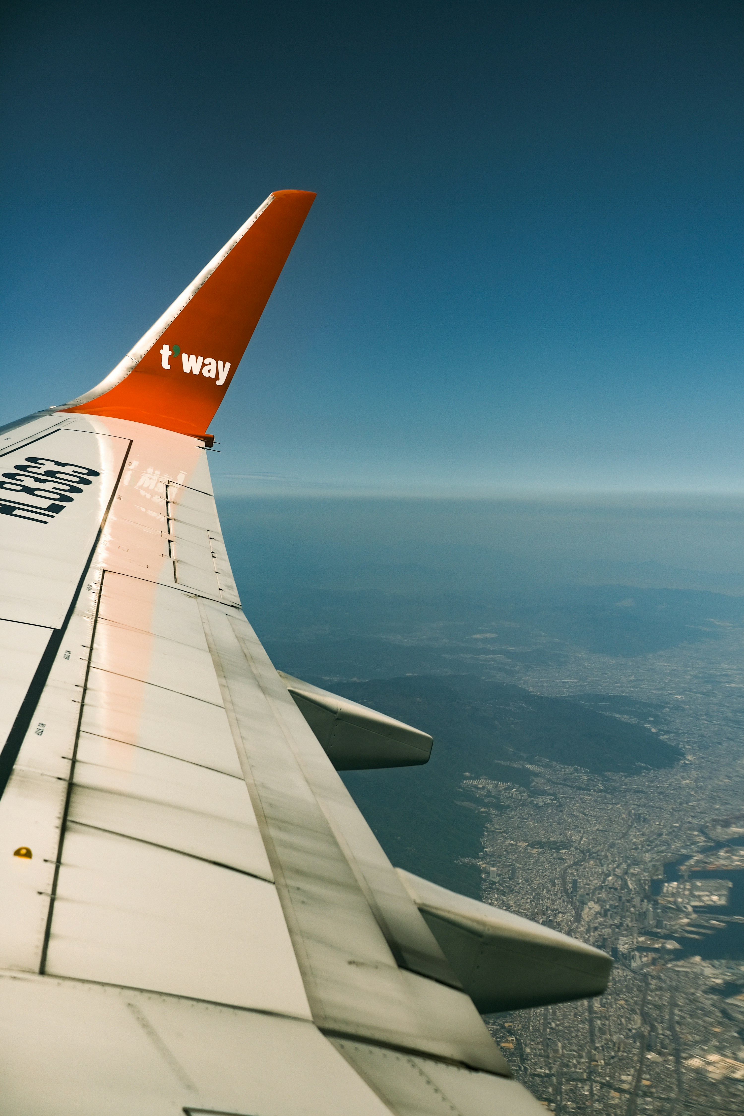The wing of an airplane flying over a city
