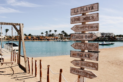 A wooden sign sitting on top of a sandy beach
