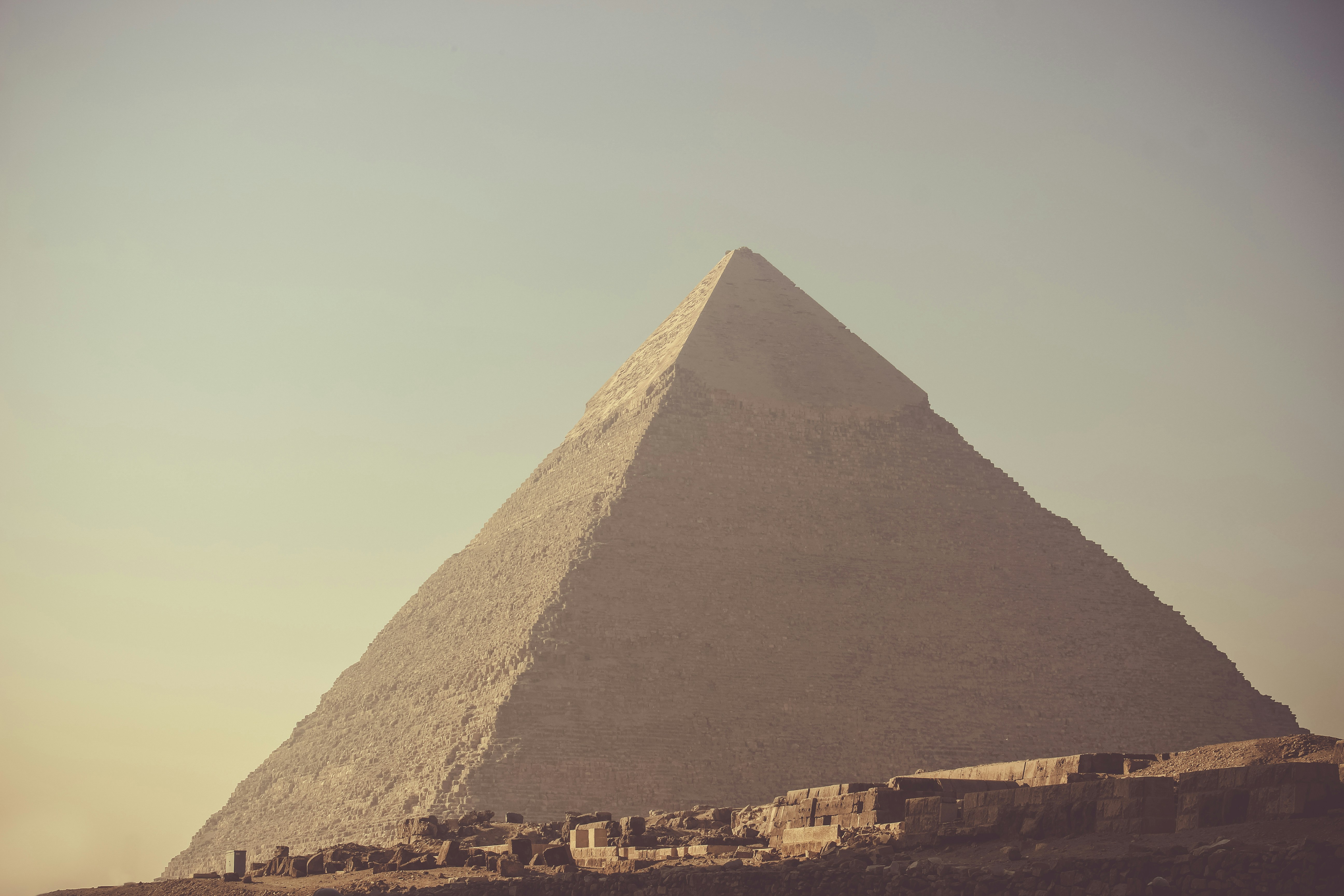 A giraffe standing in front of a very tall pyramid