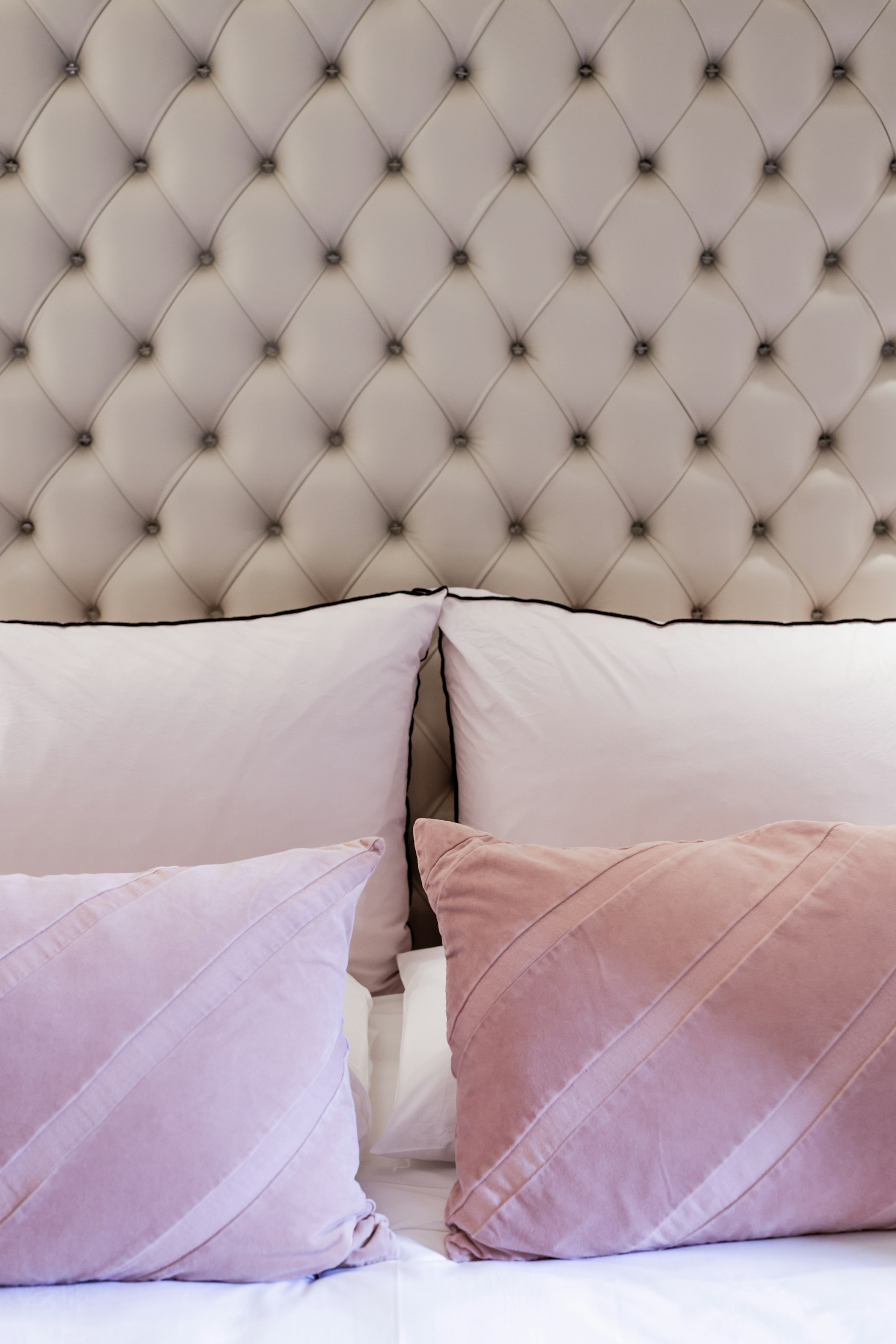 A bed with a white headboard and pink pillows