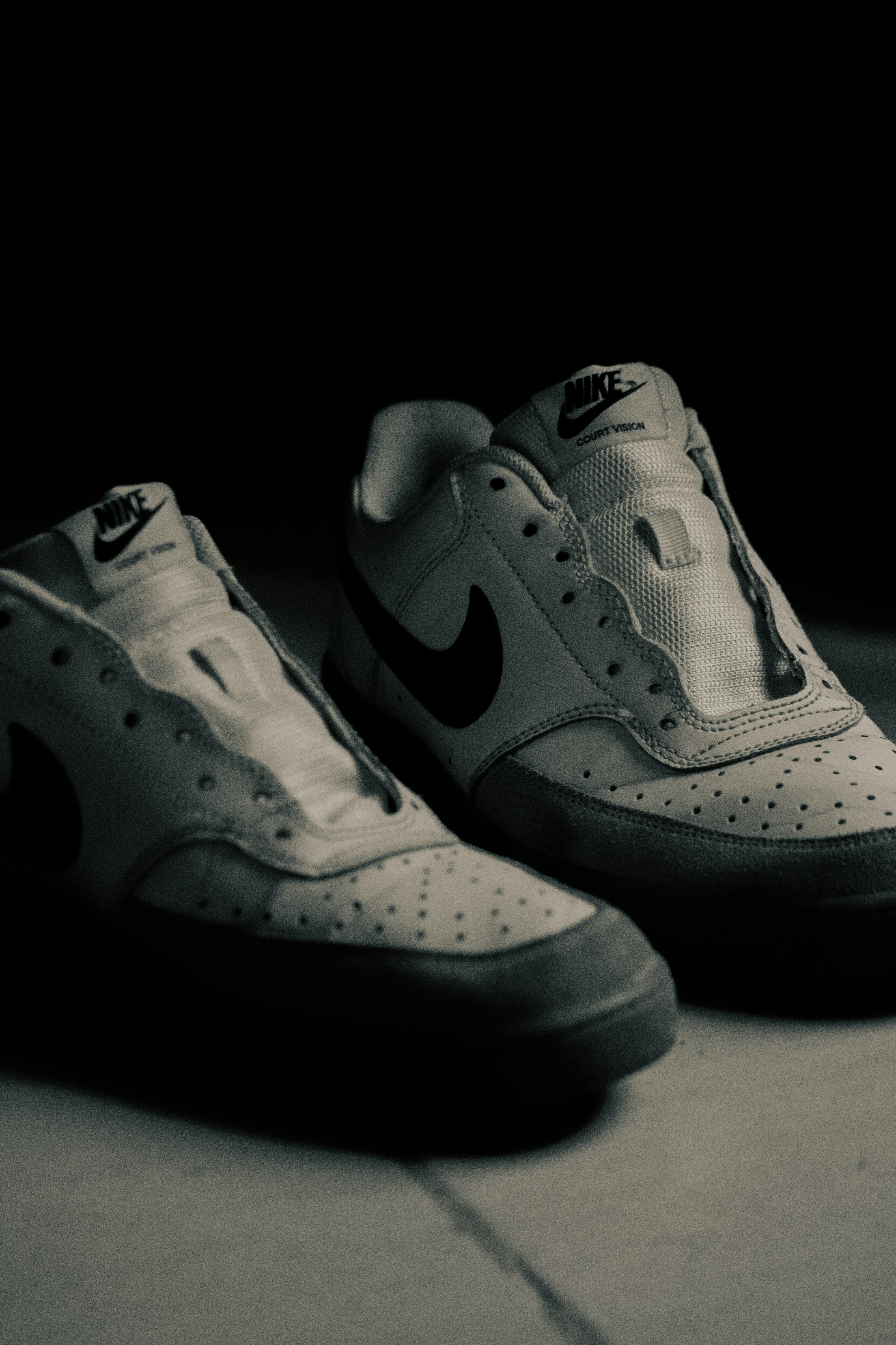 A pair of white sneakers sitting on top of a cement floor