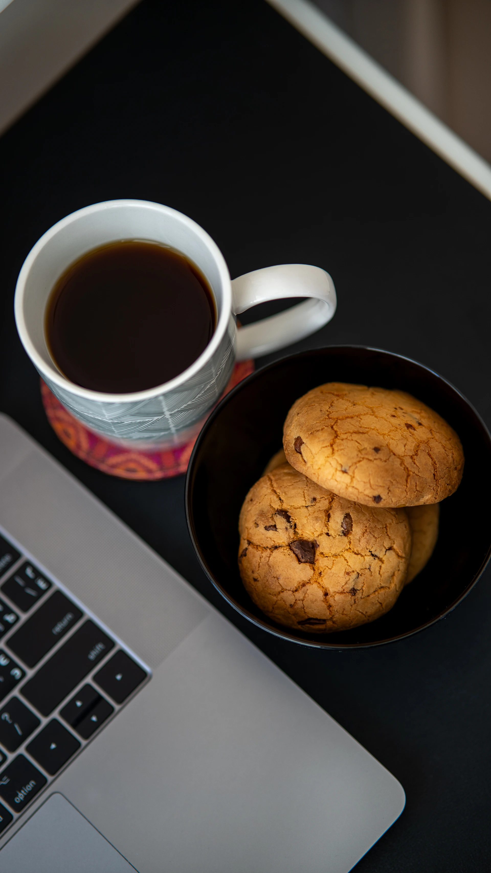 A cup of coffee next to a plate of cookies