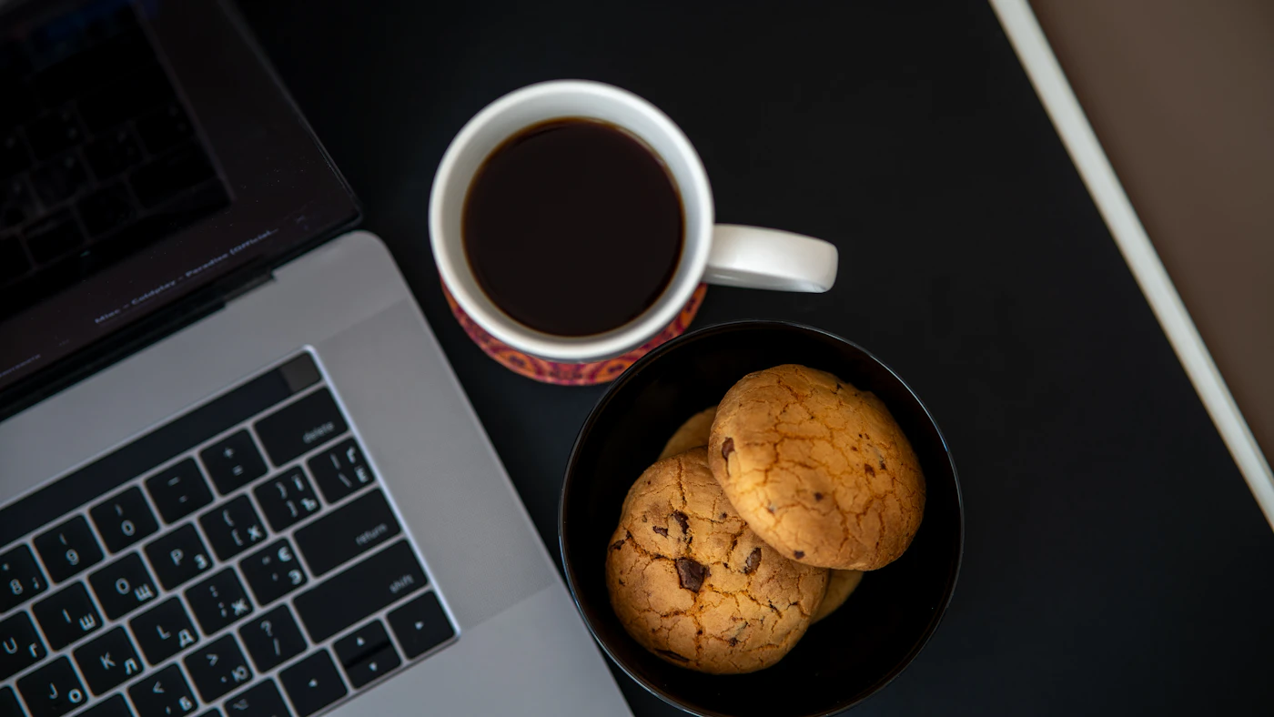 Kaffee und Laptop am Schreibtisch als Symbol für typische Rauchgewohnheiten am Morgen und bei der Arbeit