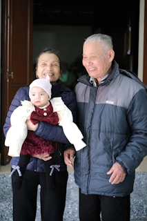 A man and a woman standing next to each other holding a baby