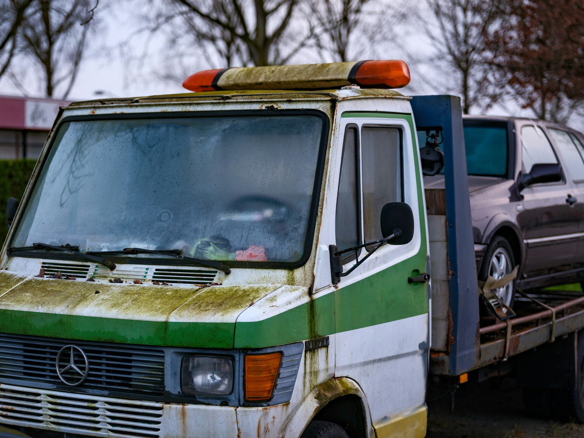 A green and white truck with a car on the back of it