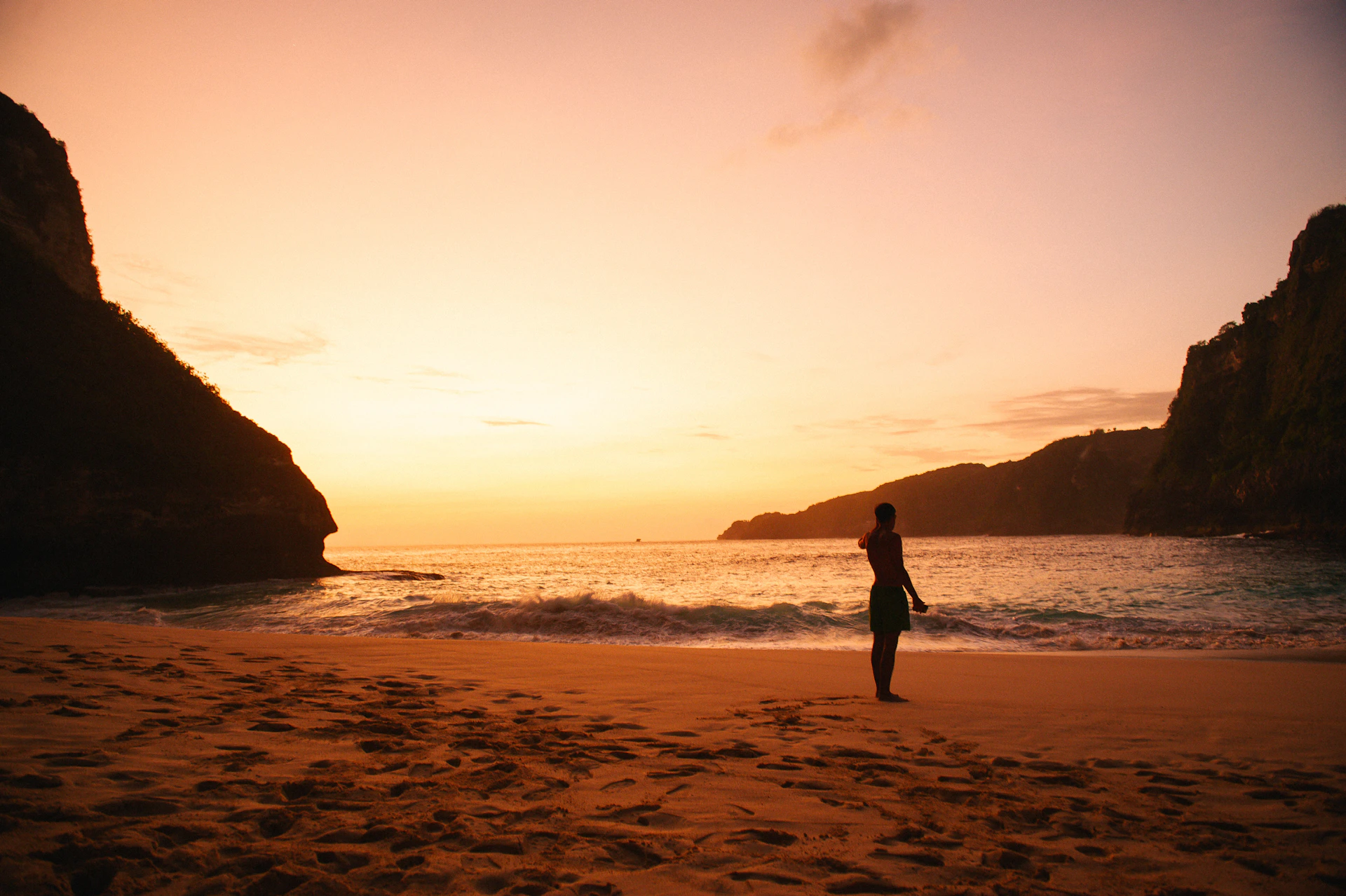 A person standing on a beach at sunset