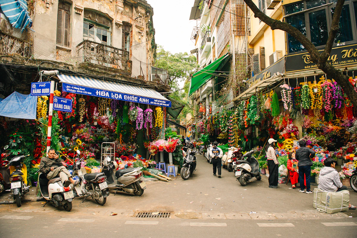 A flower-filled street corner with scooters and old shopfronts in central Hanoi