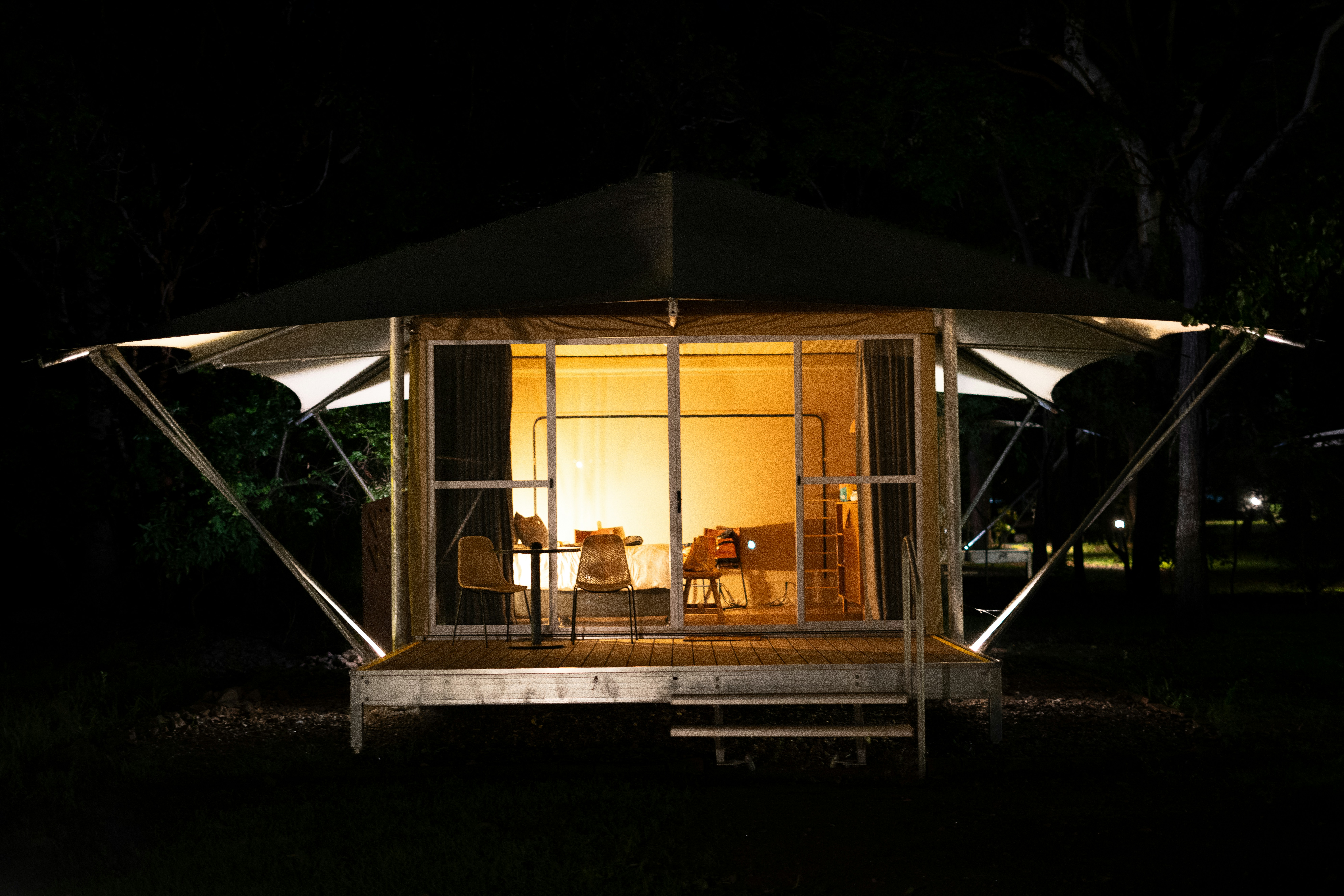 A lit up cabin in the middle of a field at night