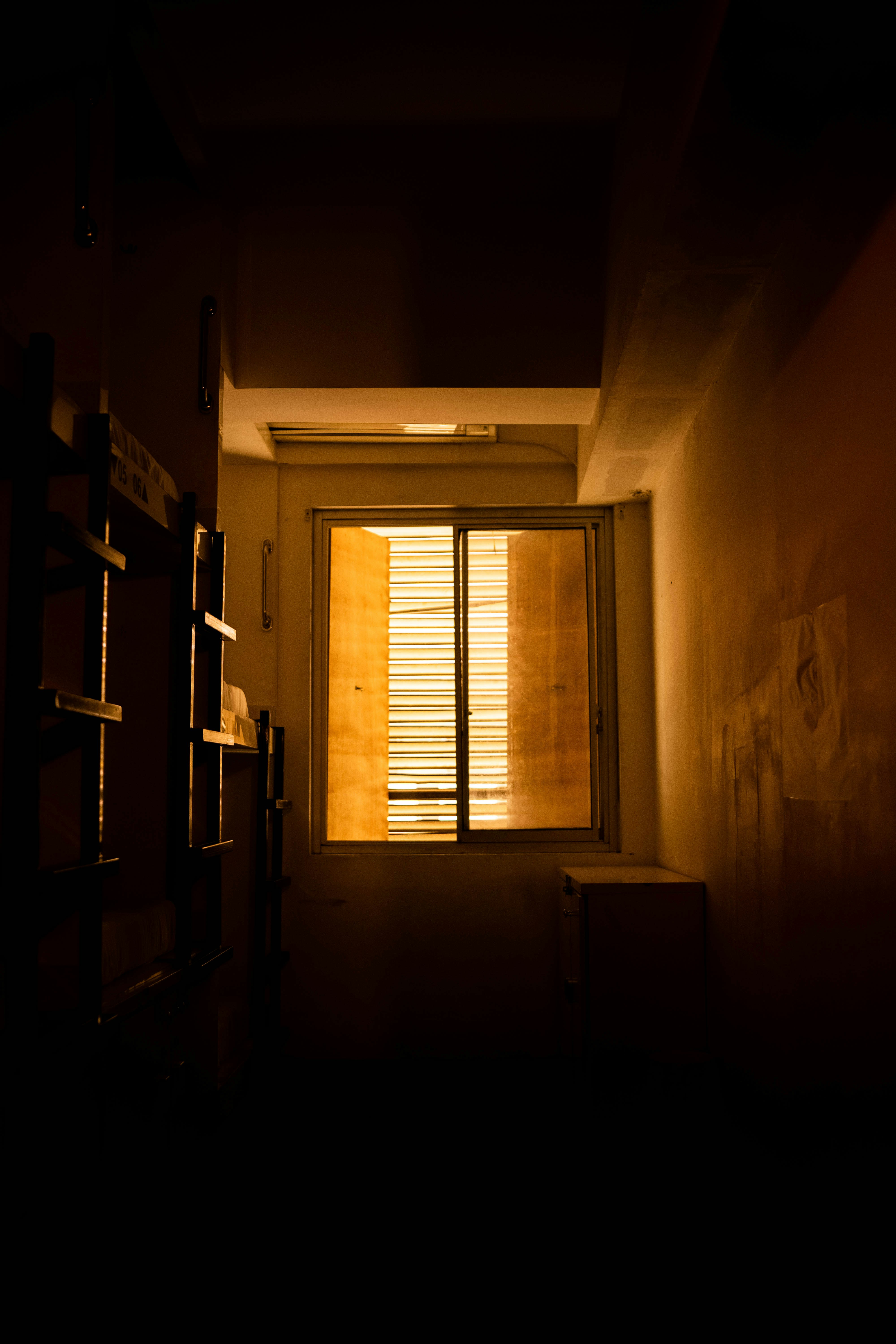 A dark hallway with a window and blinds