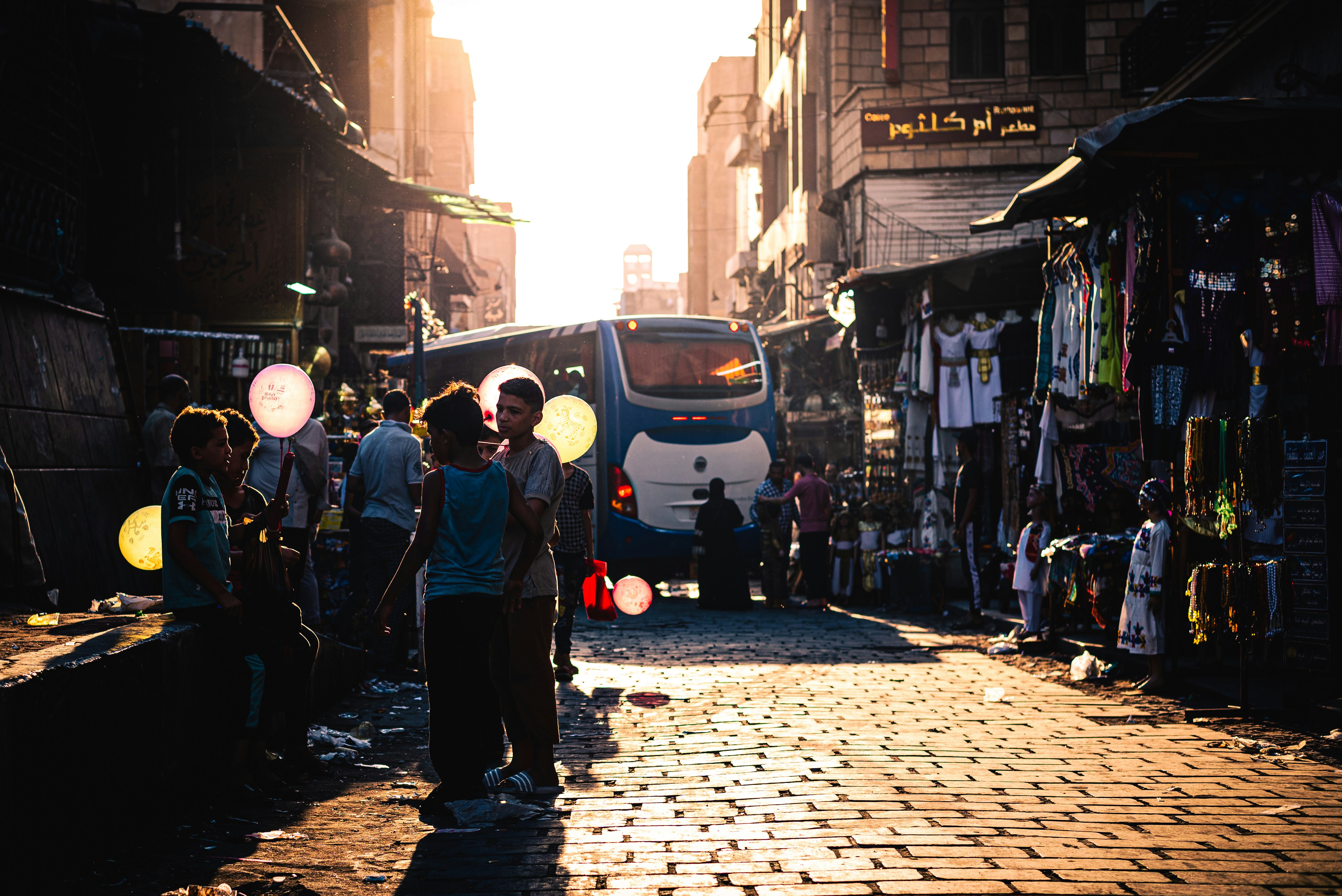 A group of people walking down a street next to tall buildings