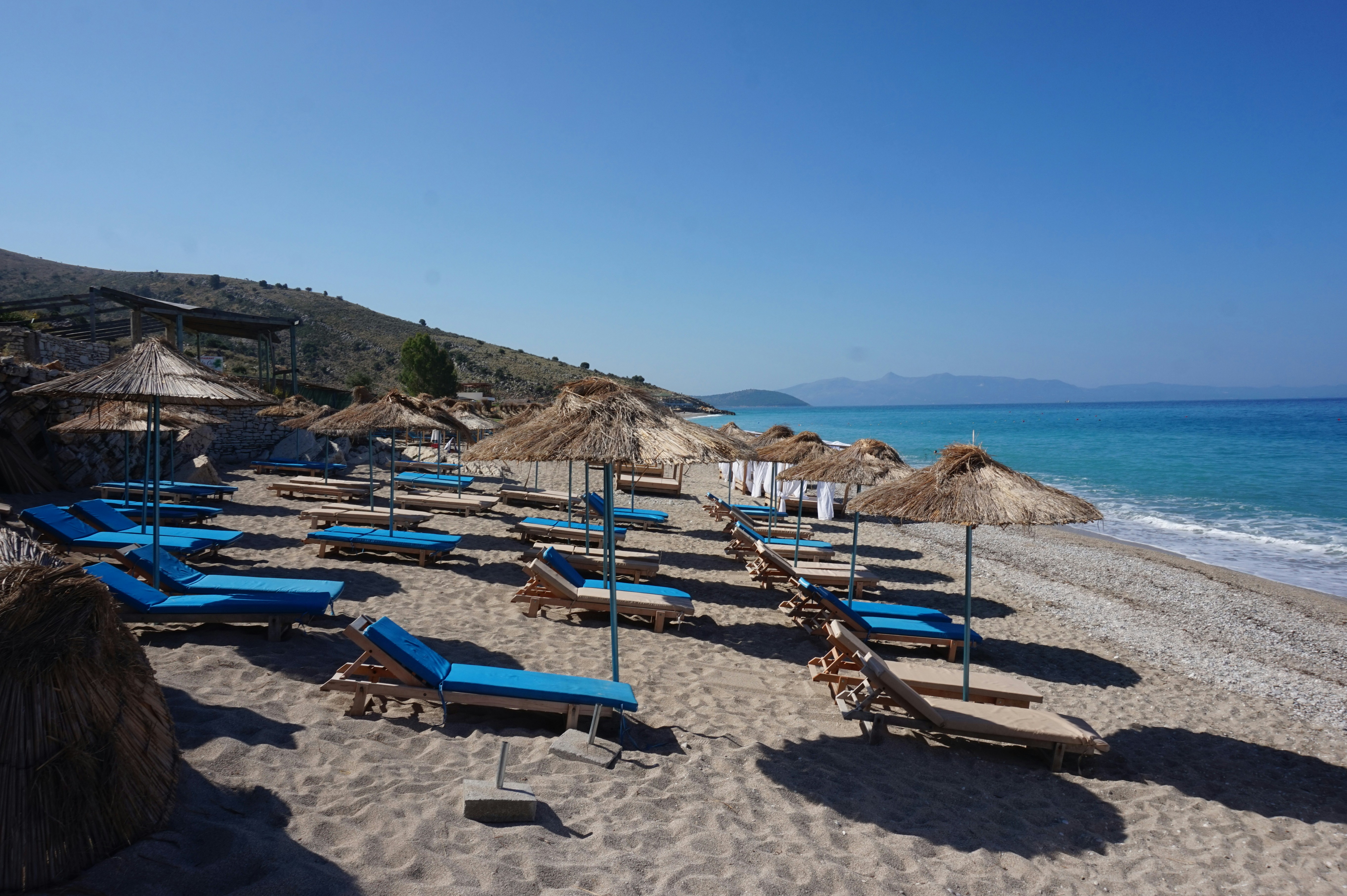 A bunch of lounge chairs and umbrellas on a beach