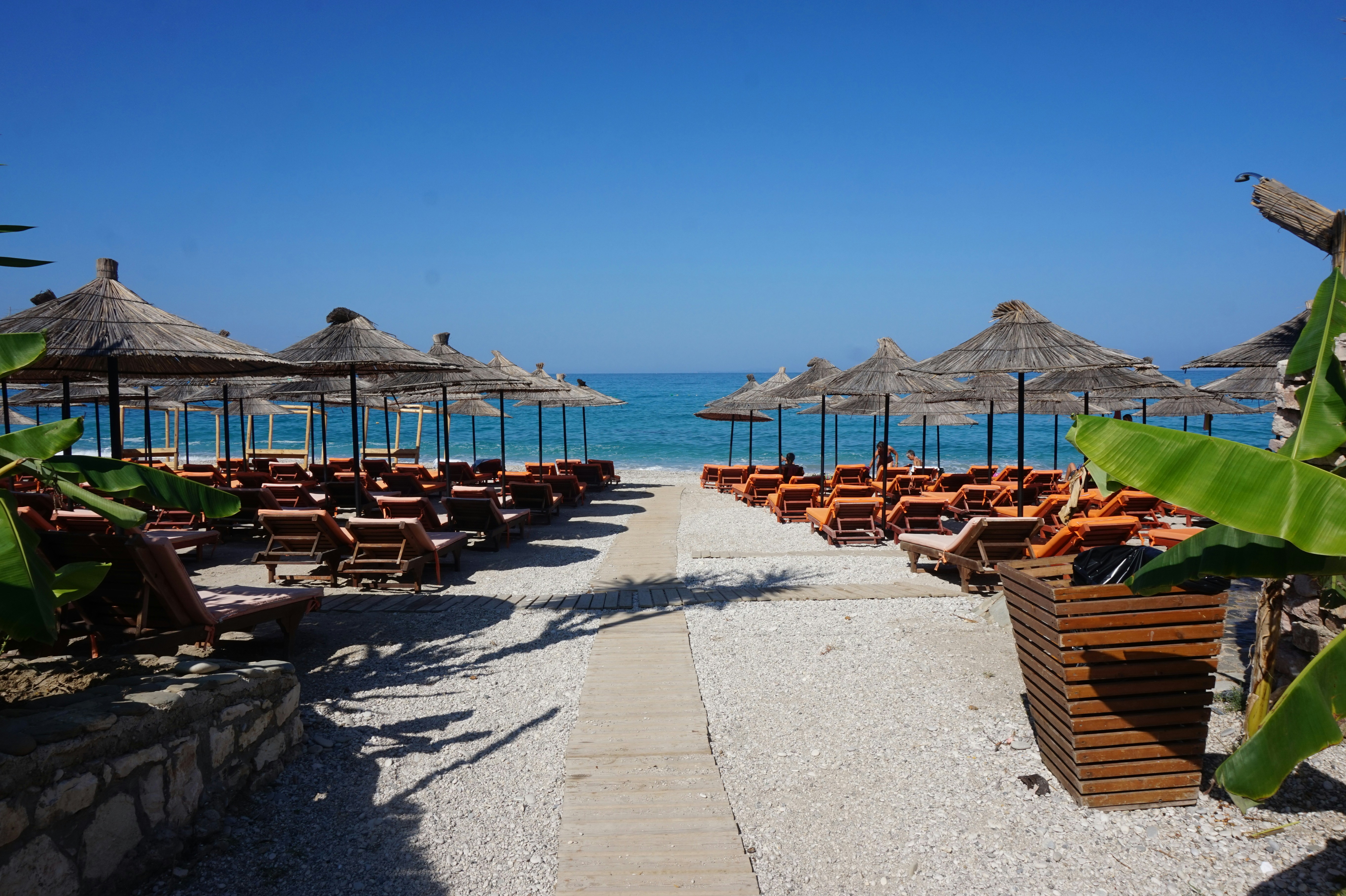 A sandy beach lined with umbrellas and chairs, Umbrellas and chairs at Lukova beach on the Albanian riviera. In the background is the ocean. When using my images please cite me as follows: Marie Volkert / Reiseblog Worldonabudget and link to my website: www.worldonabudget.de