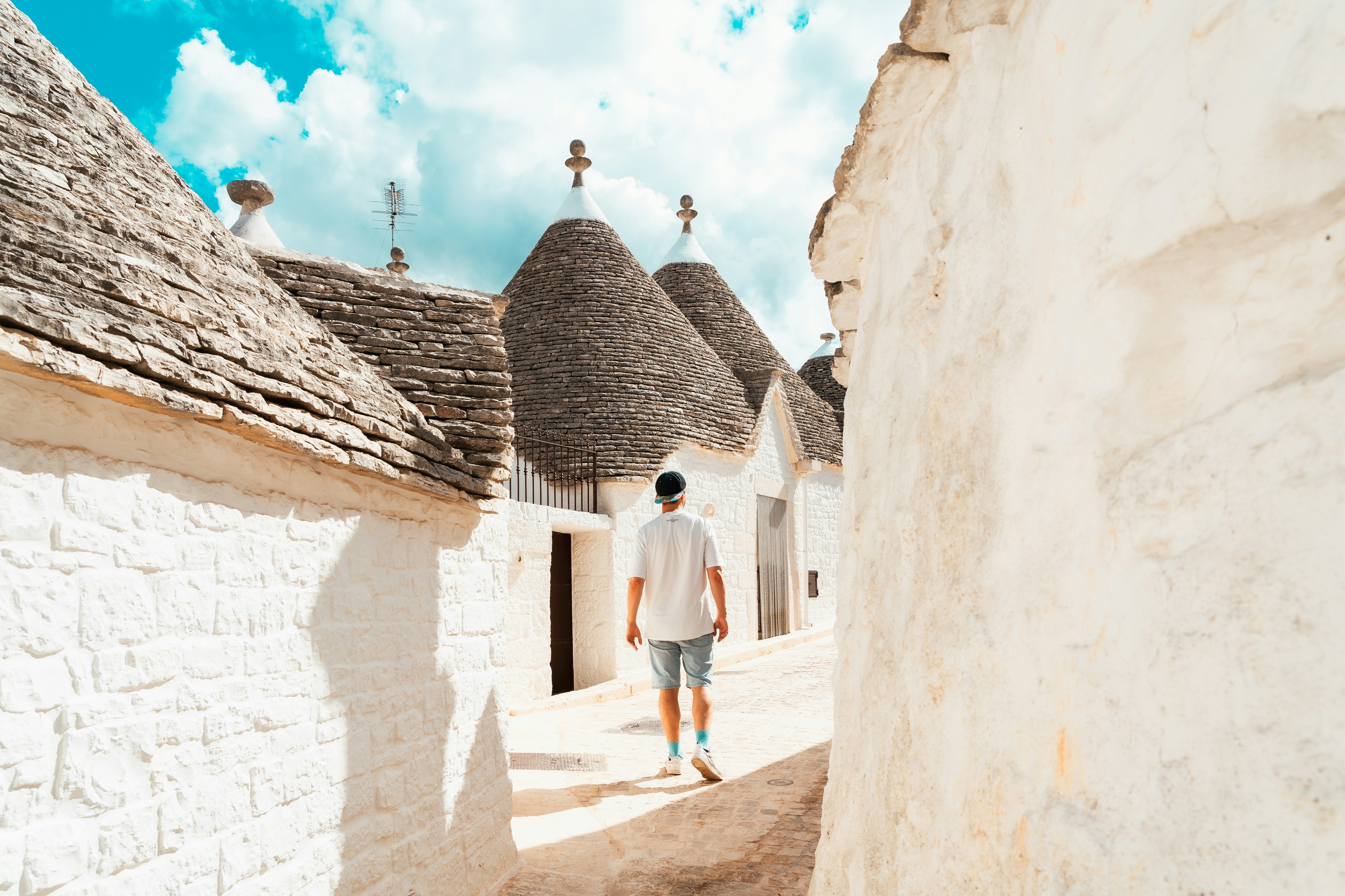 A man walking down a street next to white buildings