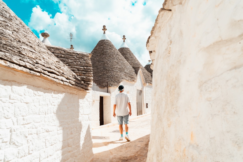 A man walking down a street next to white buildings