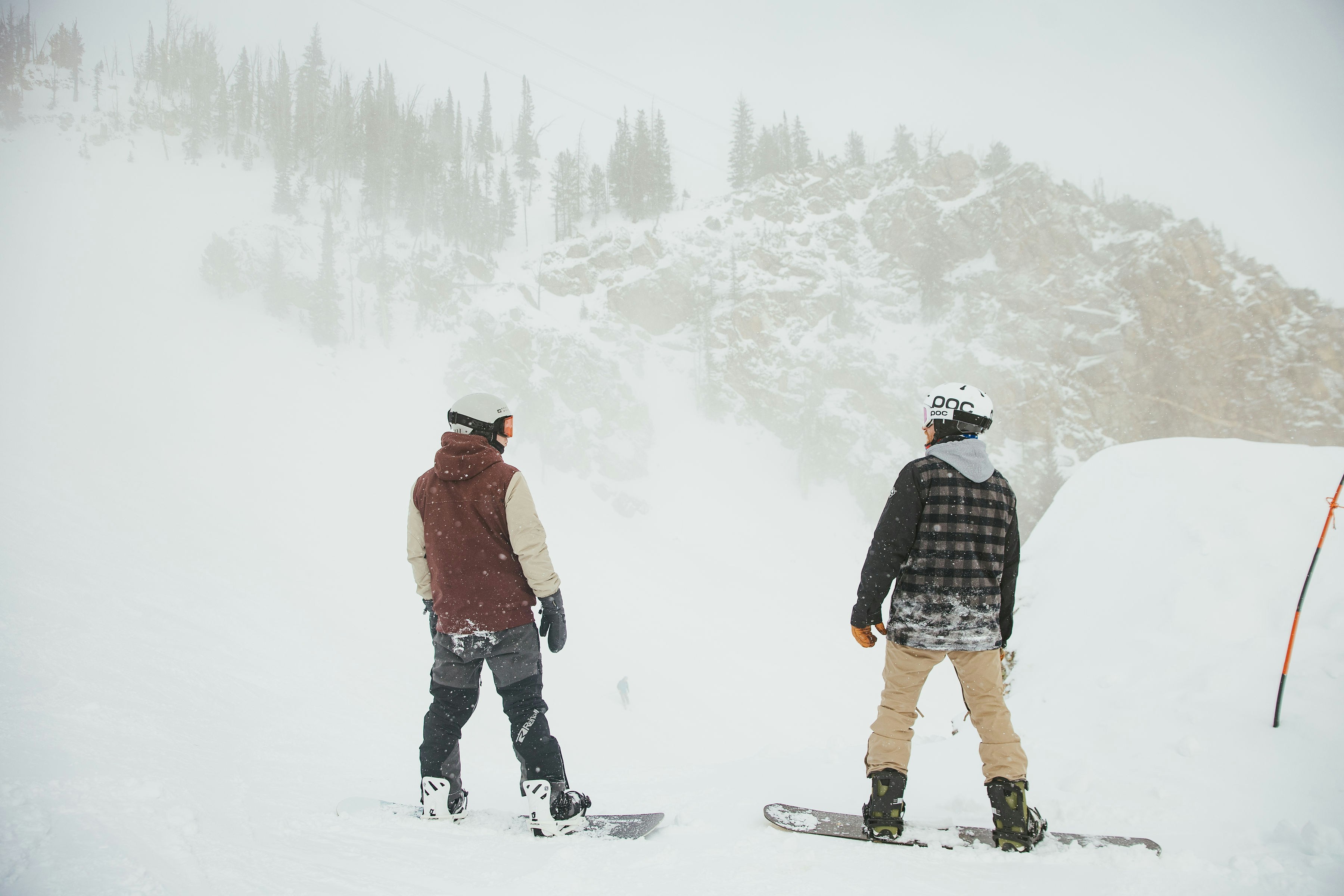 Two snowboarders are standing in the snow