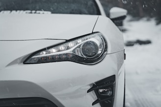 A white car driving down a snow covered road