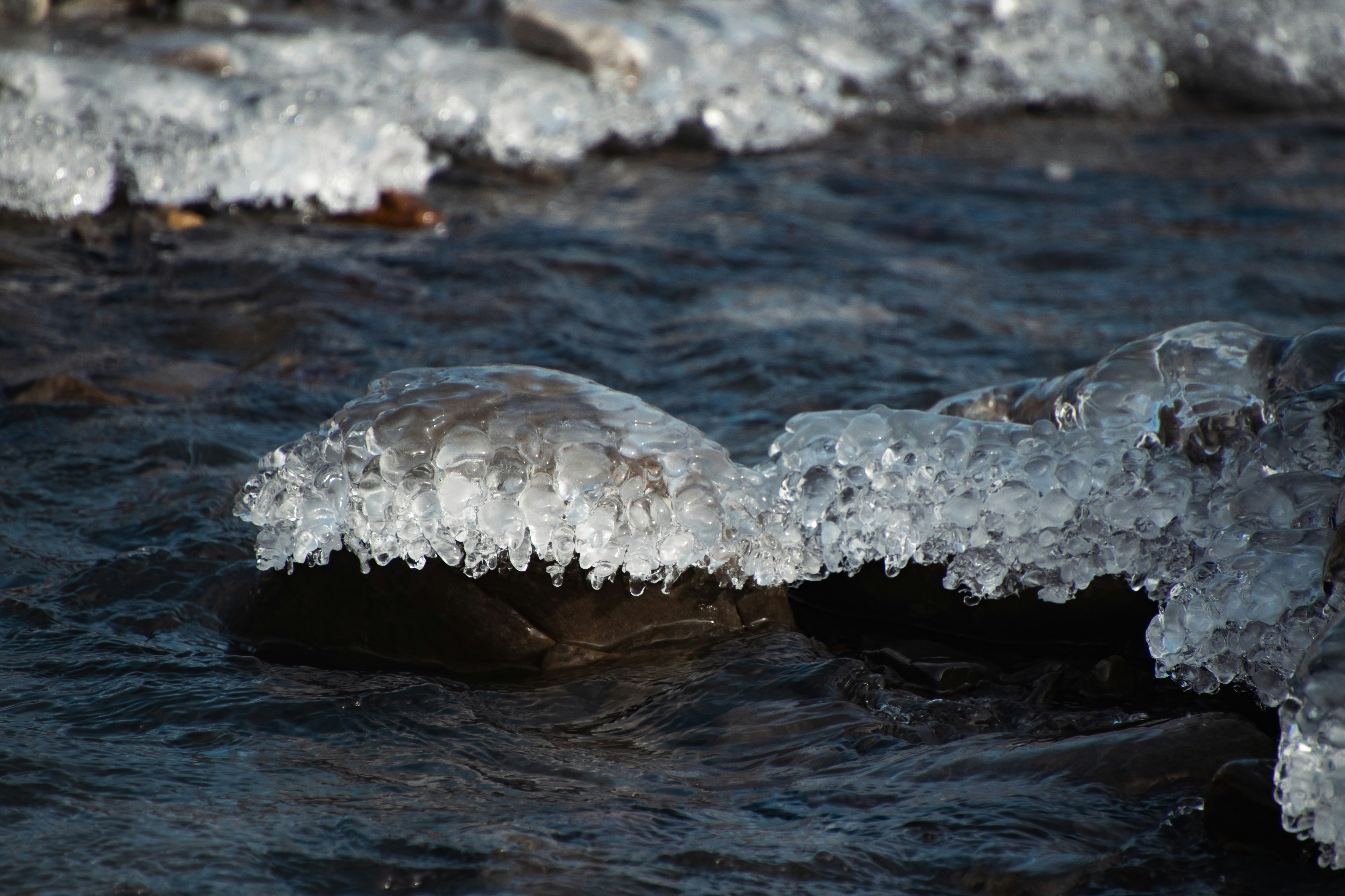 A close up of a river with ice on the rocks