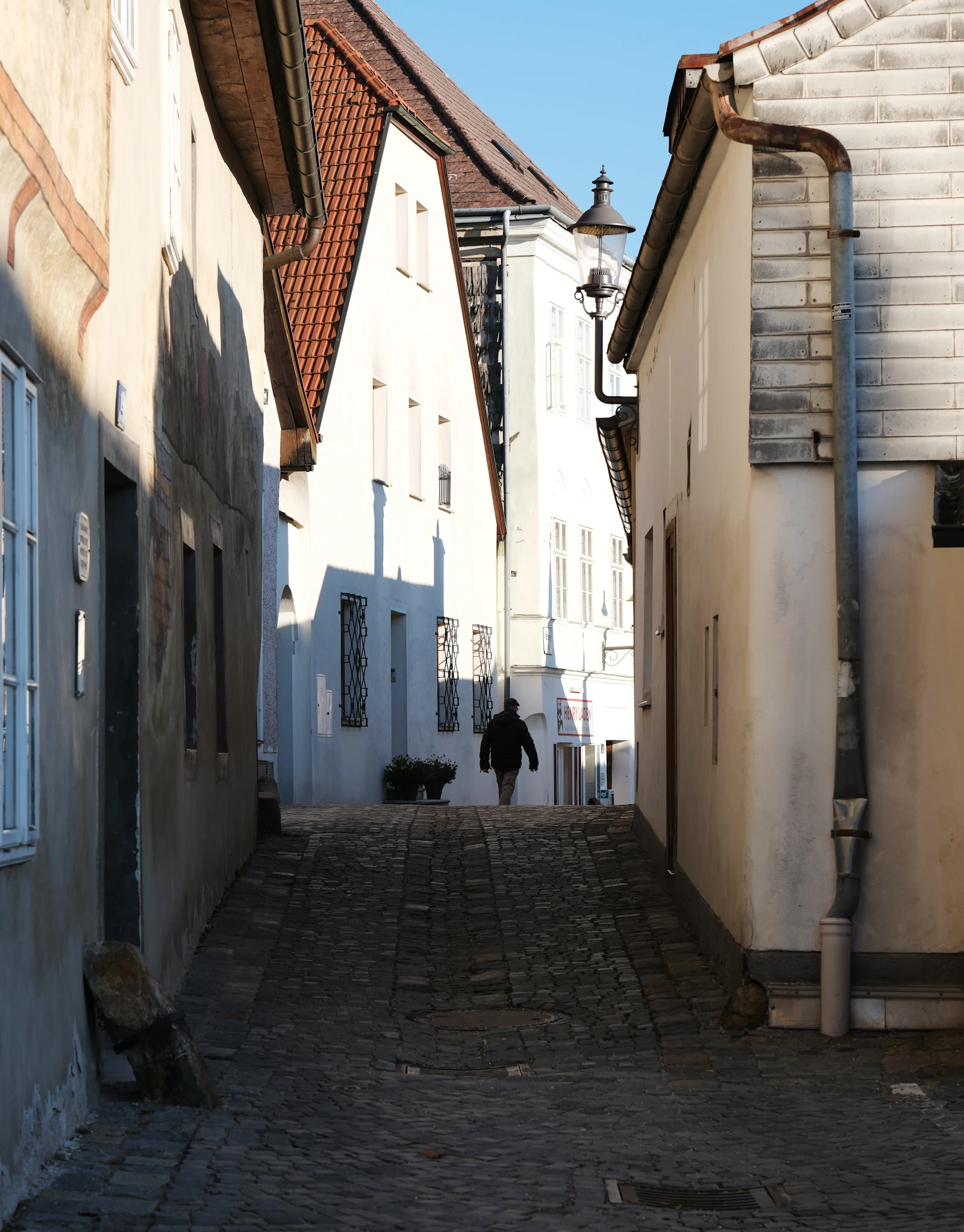 Travel photograph: A pedestrian walking down a narrow old lane between warm-coloured buildings in Melk.
