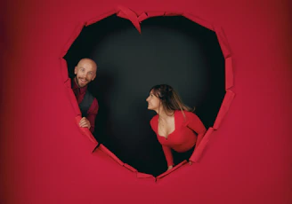 A man and a woman looking at each other through a hole in the wall