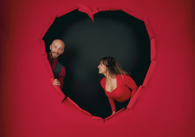 A man and a woman looking at each other through a hole in the wall