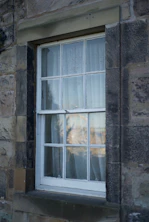 A building with a window and a cat sitting on the window sill
