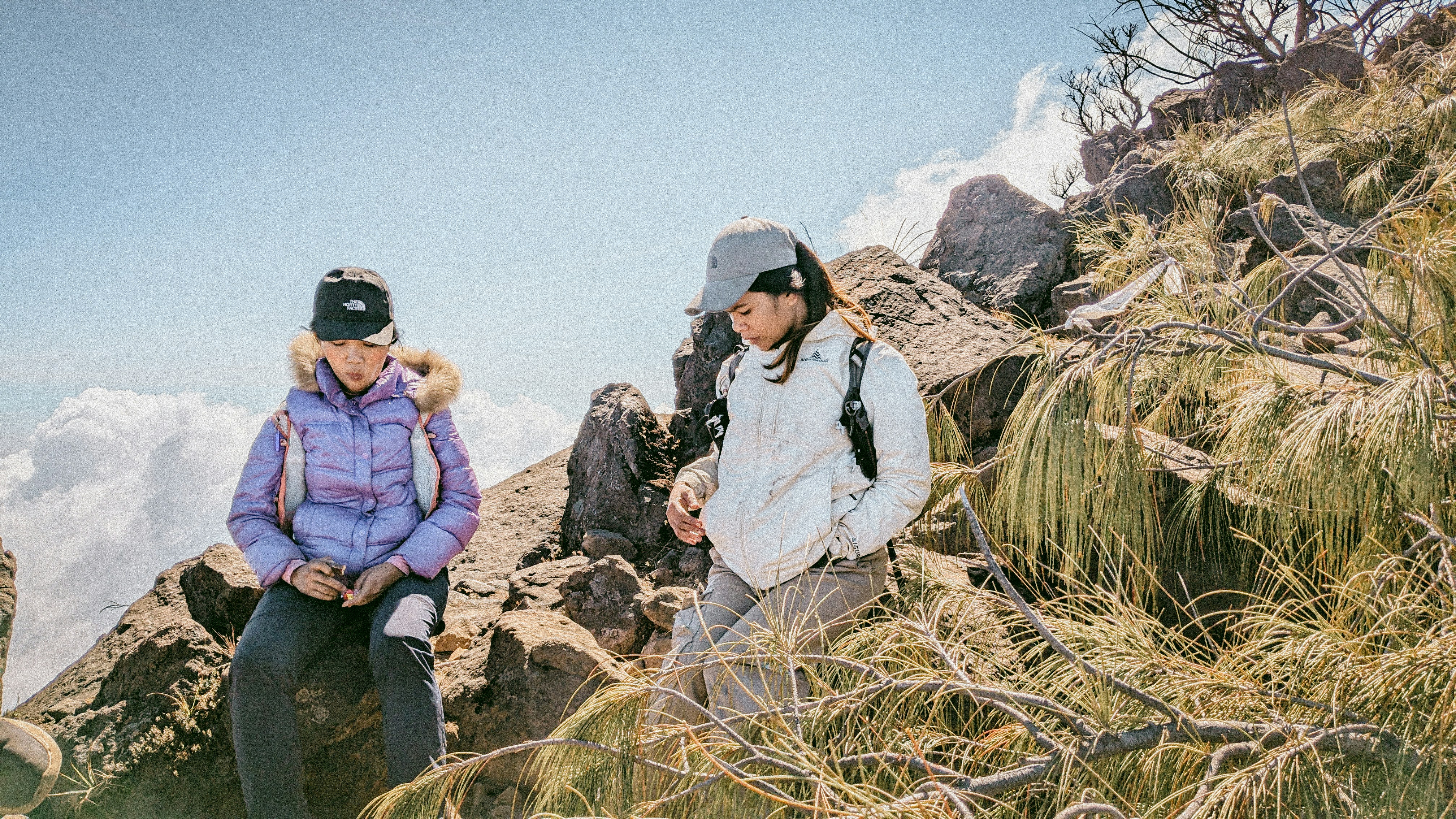 A couple of people sitting on top of a mountain