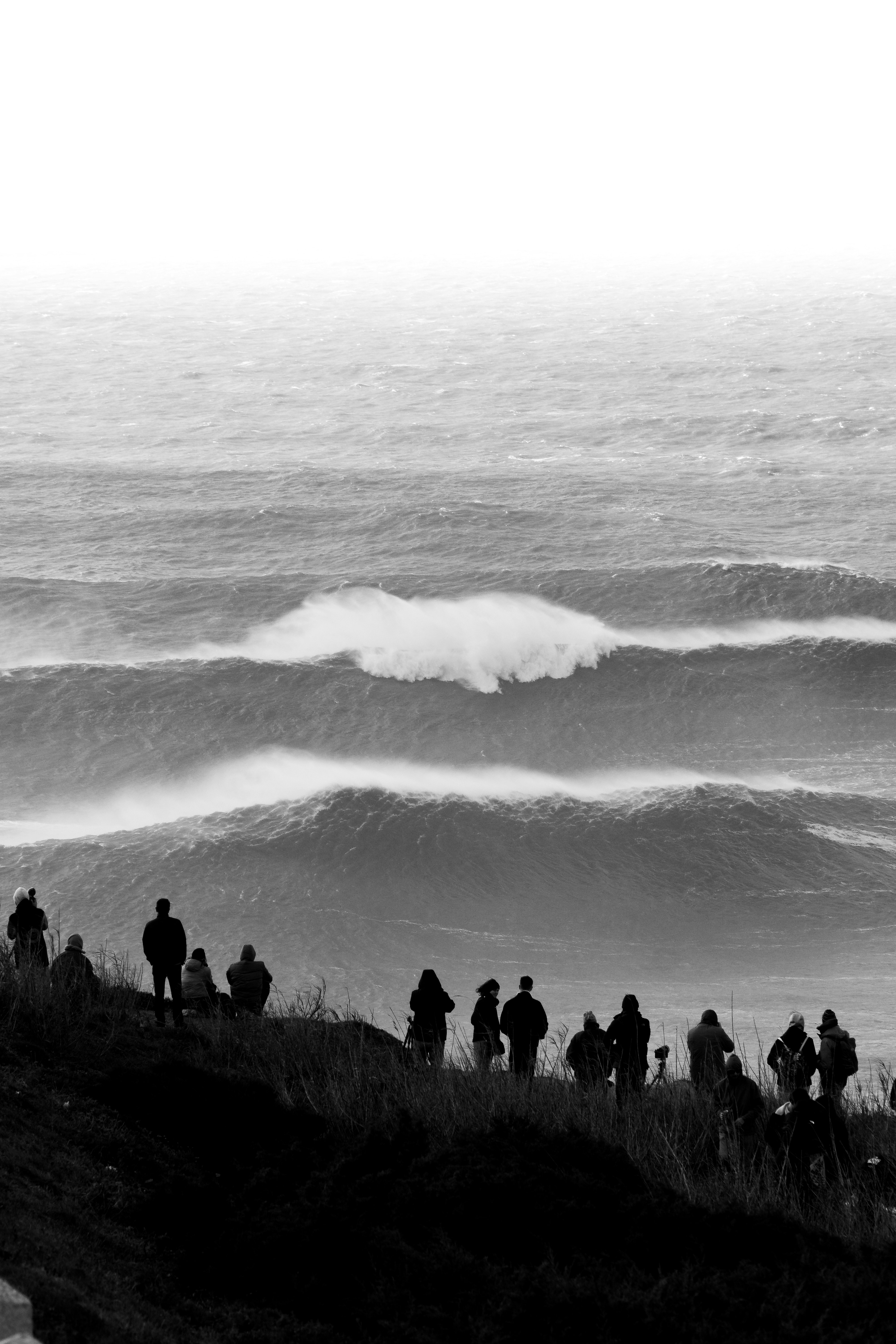 A group of people standing on top of a cliff near the ocean