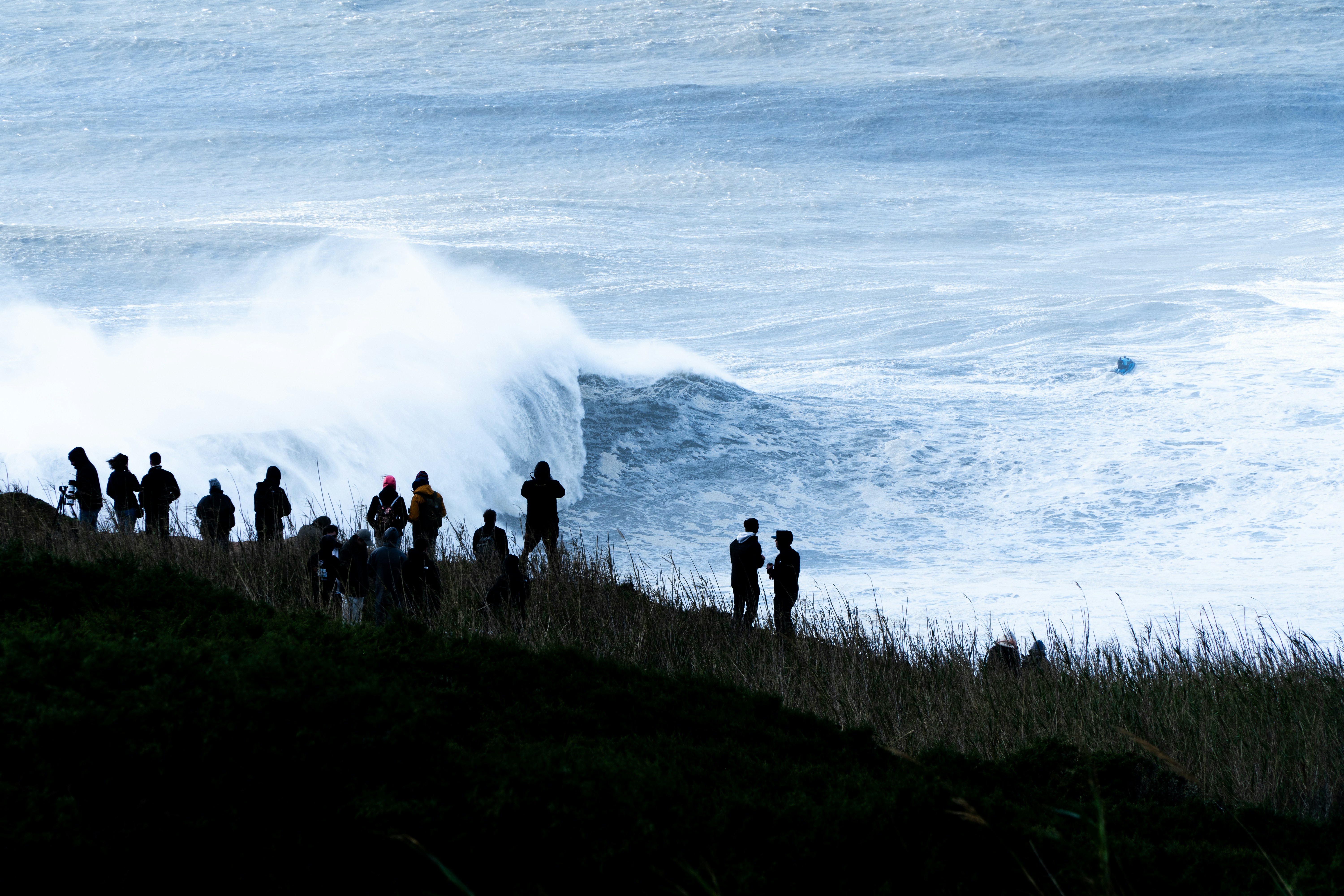 A group of people standing on top of a hill near the ocean
