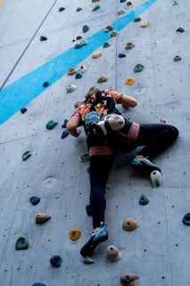 A woman is climbing up a climbing wall