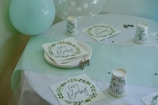 A table topped with plates and cups next to a balloon