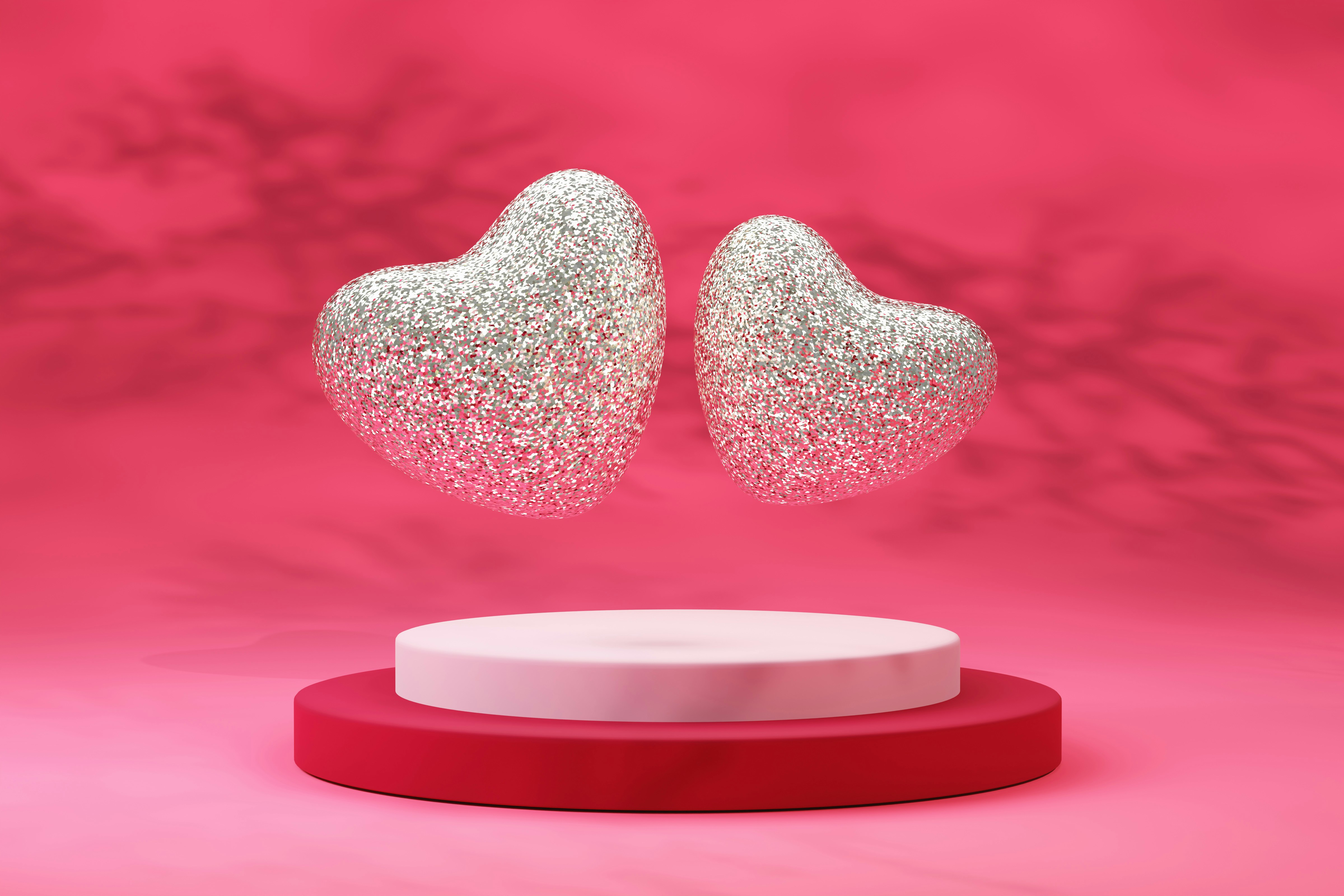 Ein Paar weiße herzförmige Ohrringe auf rosa Hintergrund