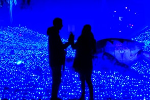 A couple of people standing in front of a blue light