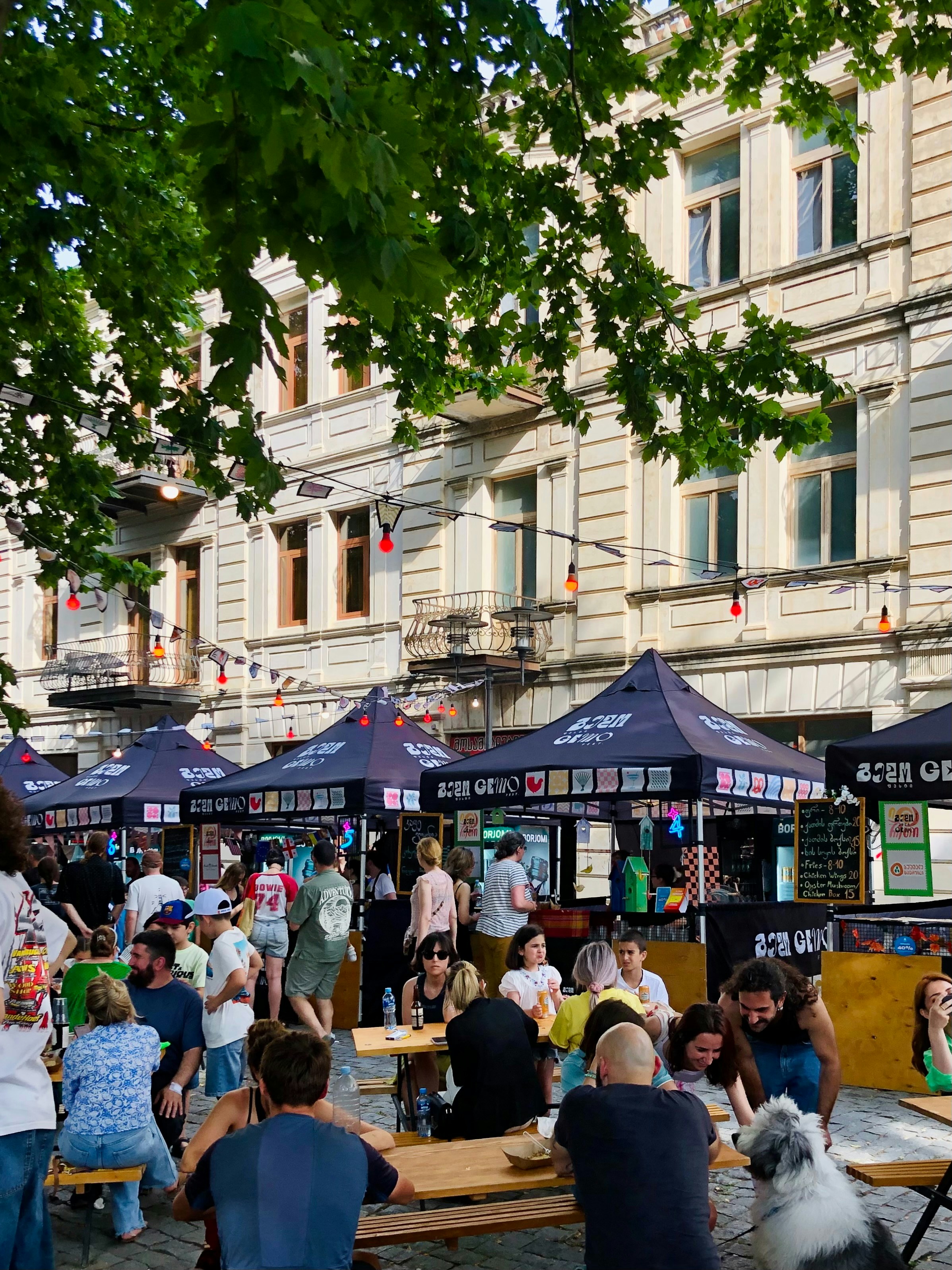 A group of people sitting at tables in front of a building