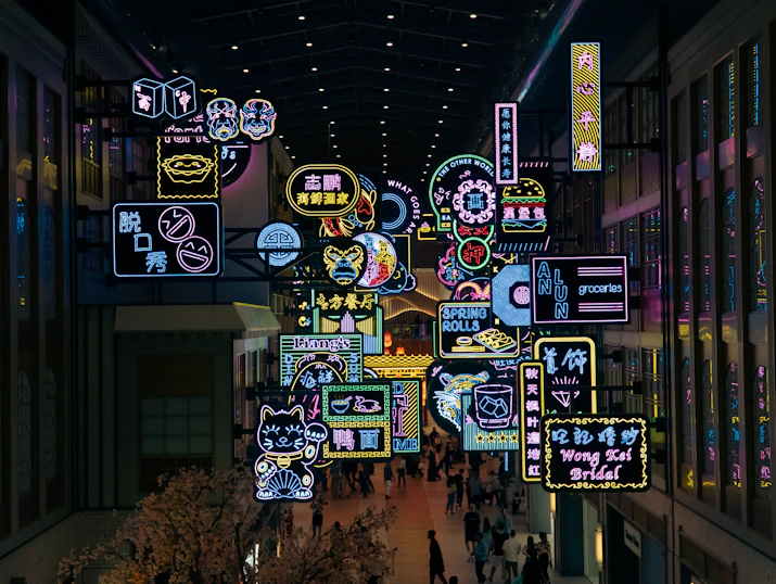 A group of people walking through a mall filled with neon signs
