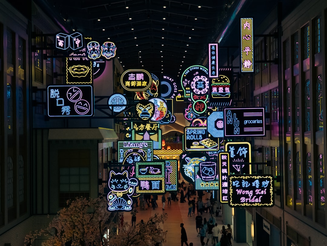 A group of people walking through a mall filled with neon signs,