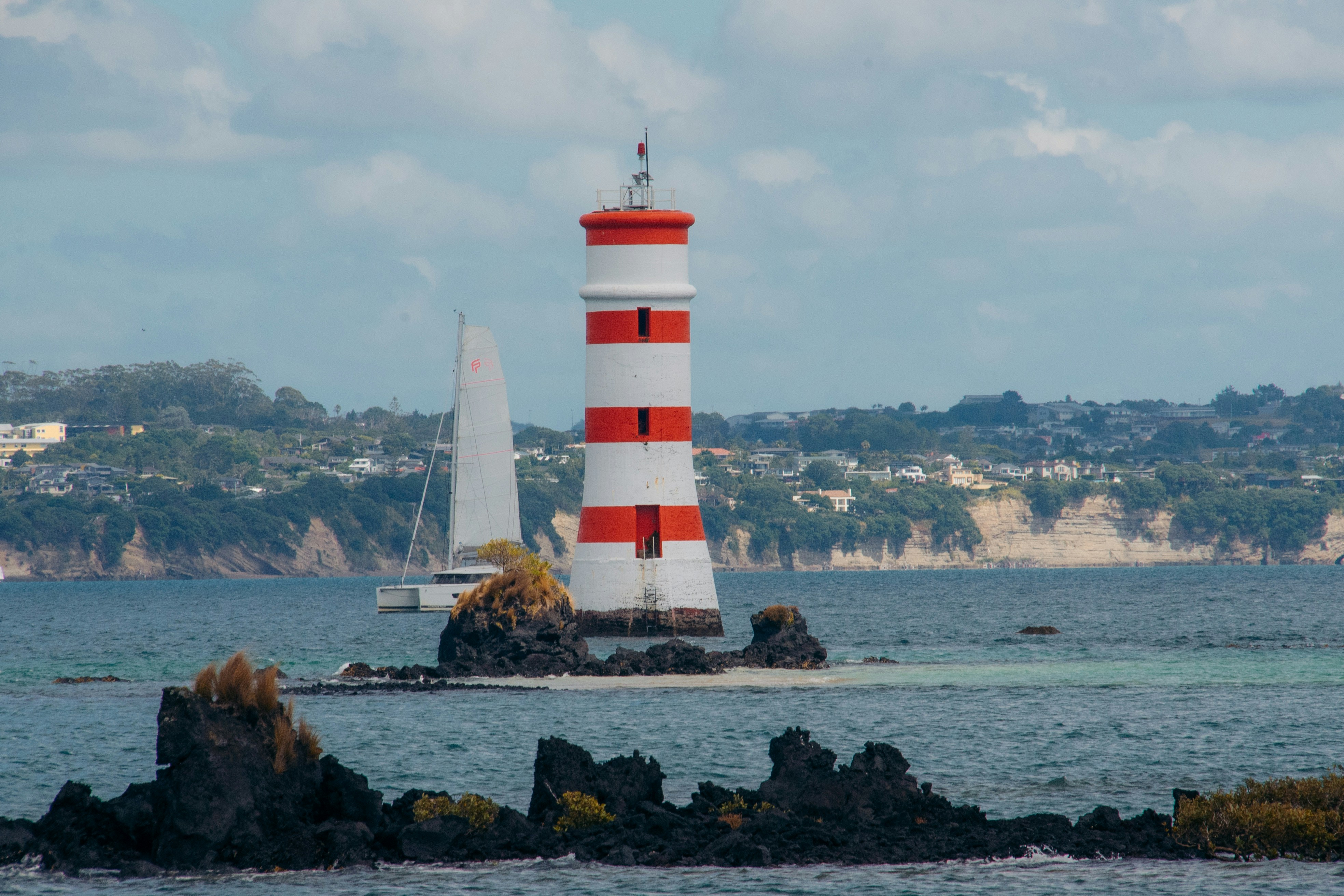 Un phare rouge et blanc posé au sommet d’un rivage rocheux photo ...