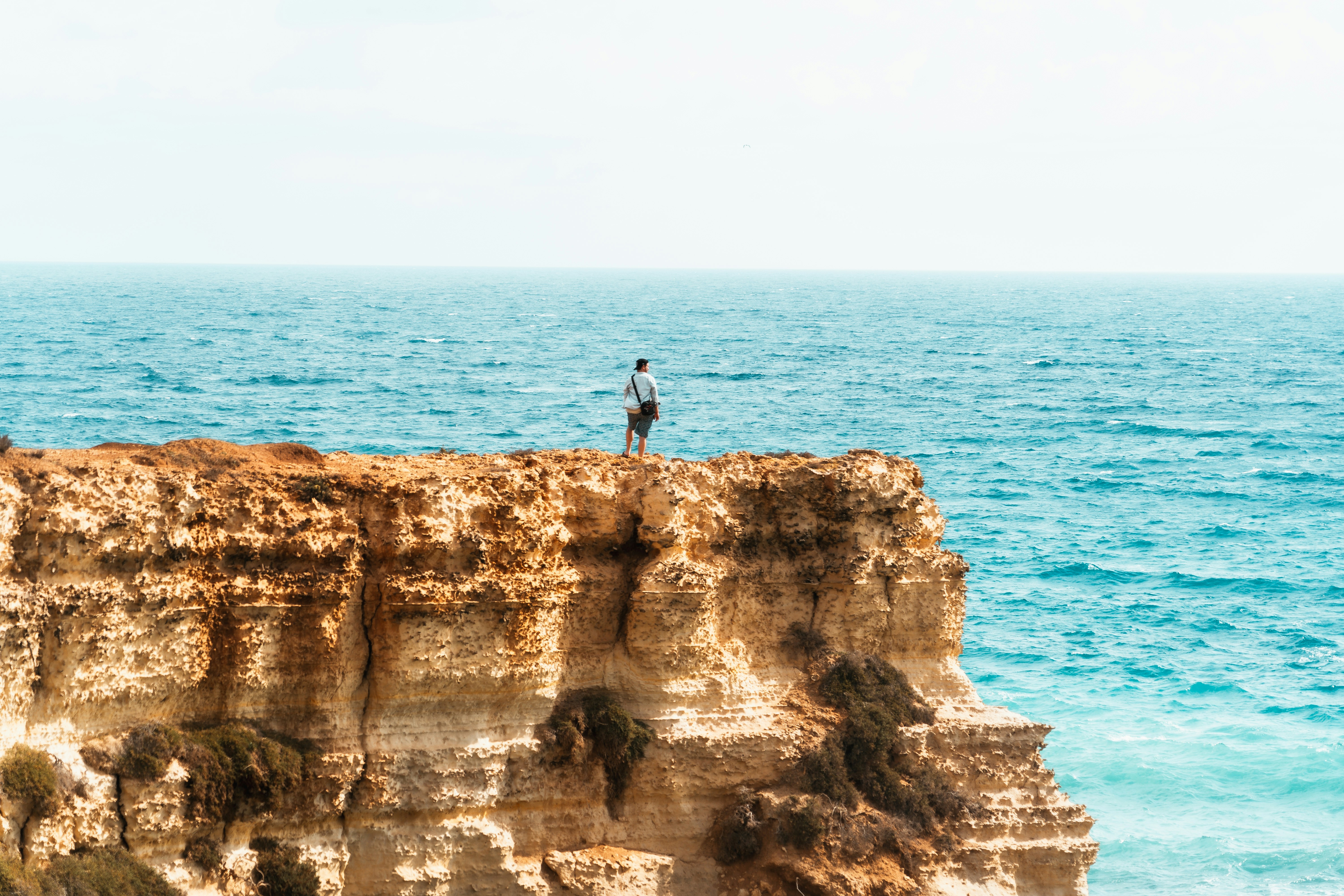 A man standing on top of a cliff next to the ocean