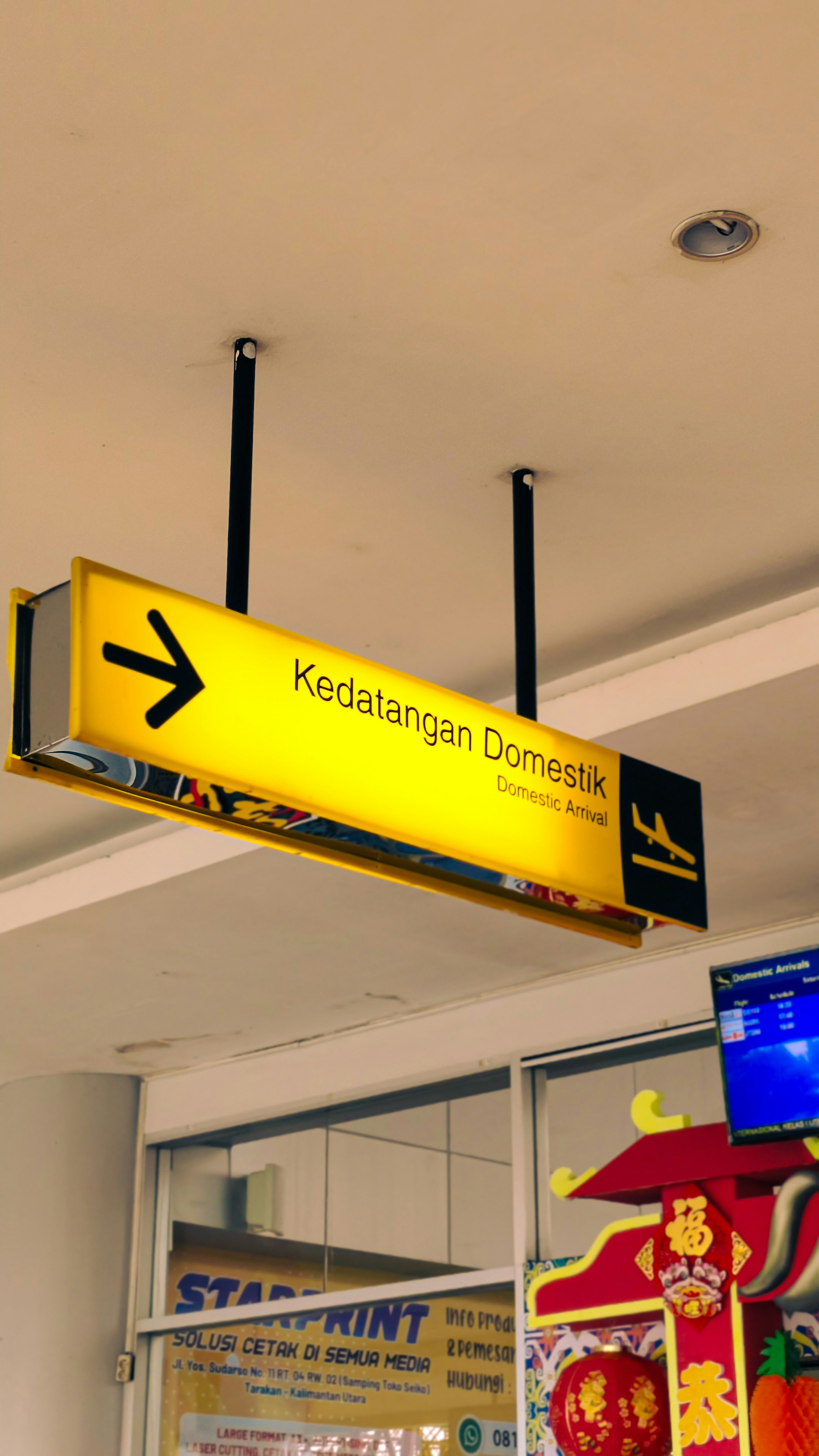 A yellow sign hanging from the ceiling of a store